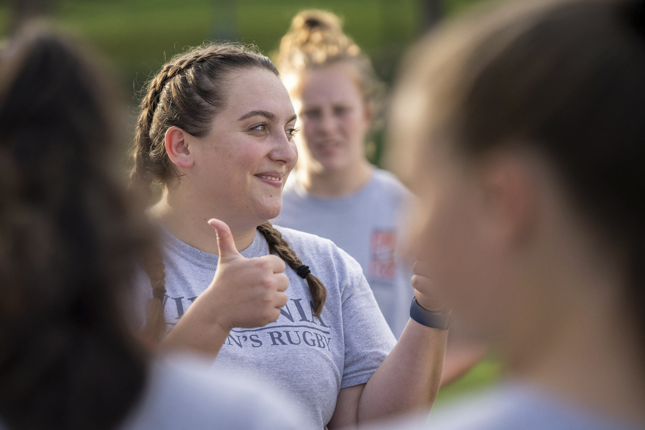 Woman on the Woman's Rugby team giving thumbs up to her teammates