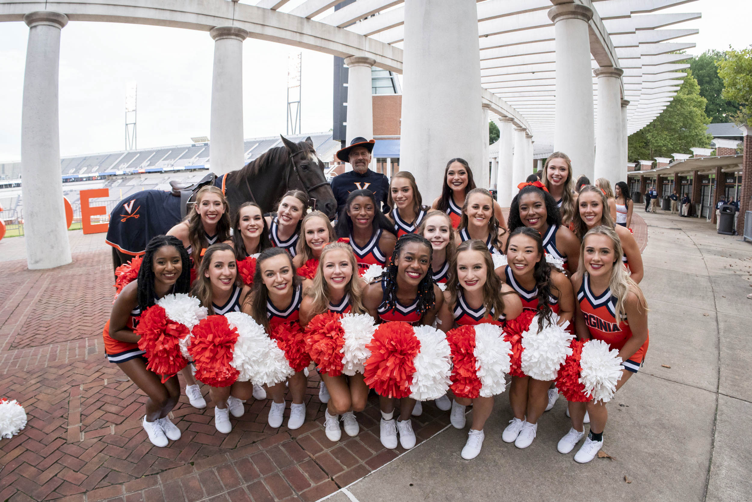 UVA cheerleaders stand beside and in front of the UVA horse and Cavalier