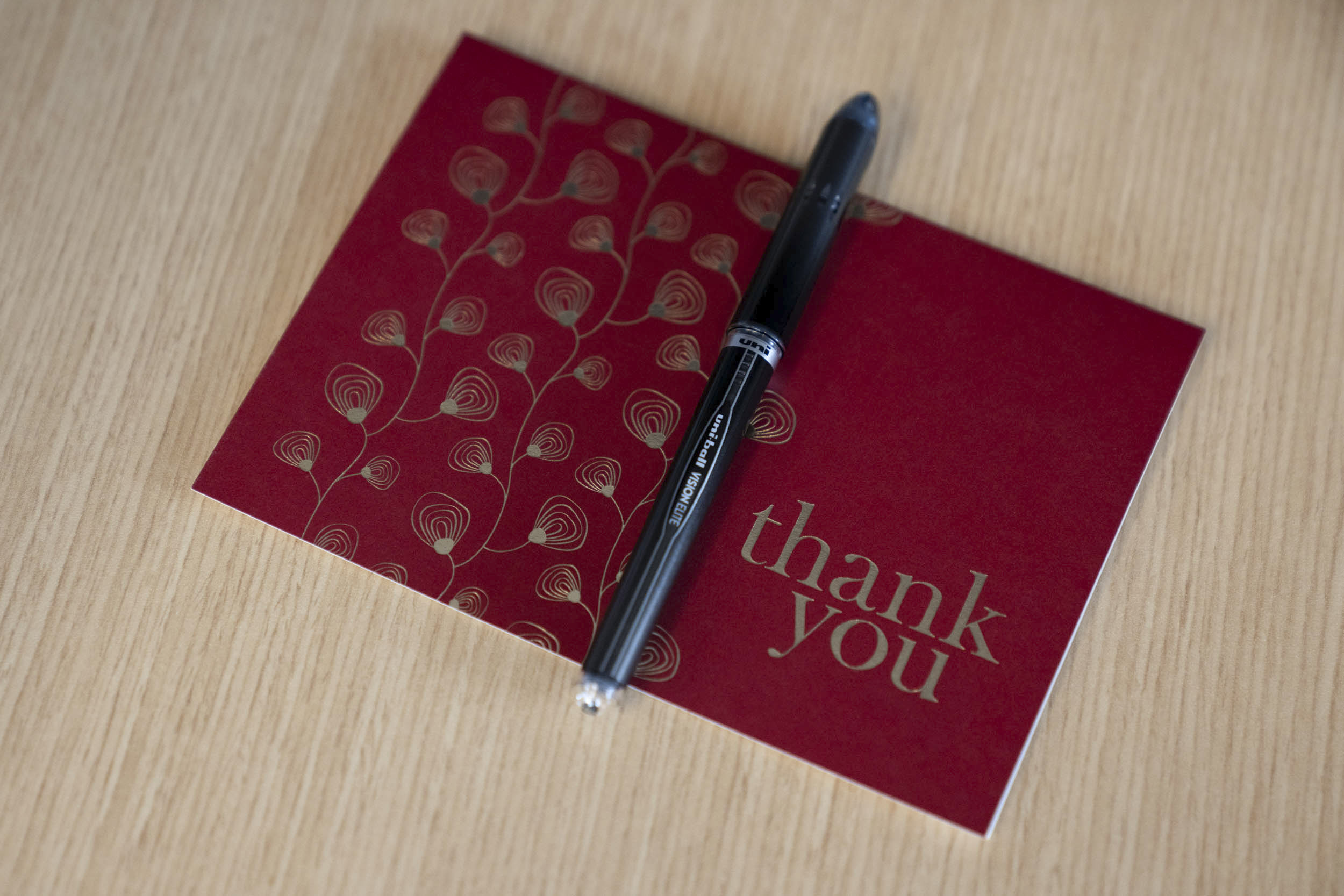 Red Thank you card with a pen on top of it