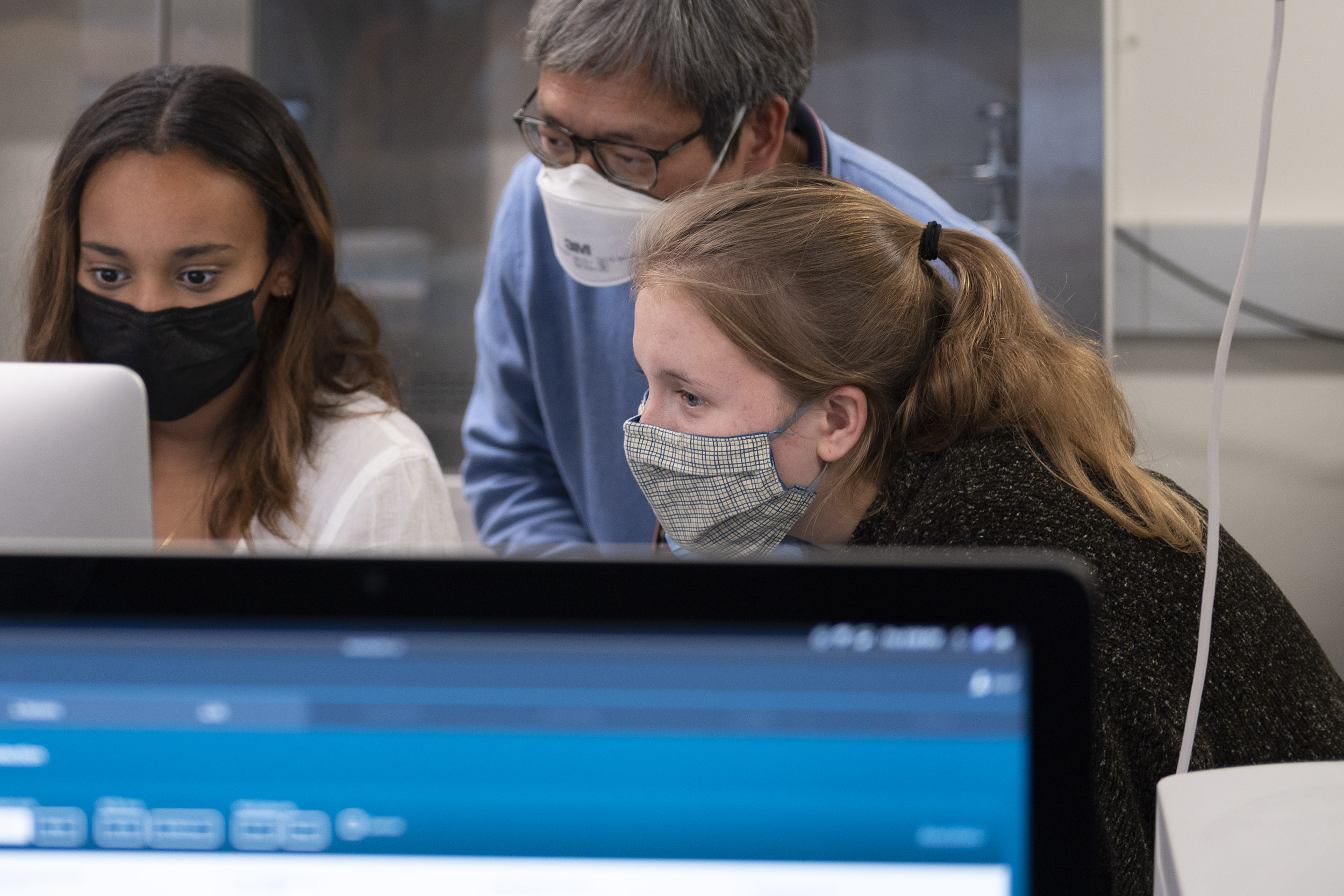 Bethlehem Judah (left) and Simonne Guenette (right) analyze real life DNA sequencing with professor Martin Wu (middle) on a computer