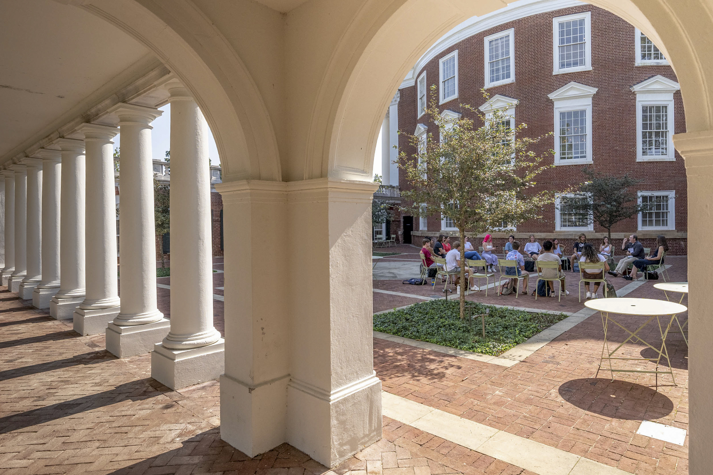 Looking through the arched entrance way to the Rotunda quart yard at a class sitting in metal chairs in a circle