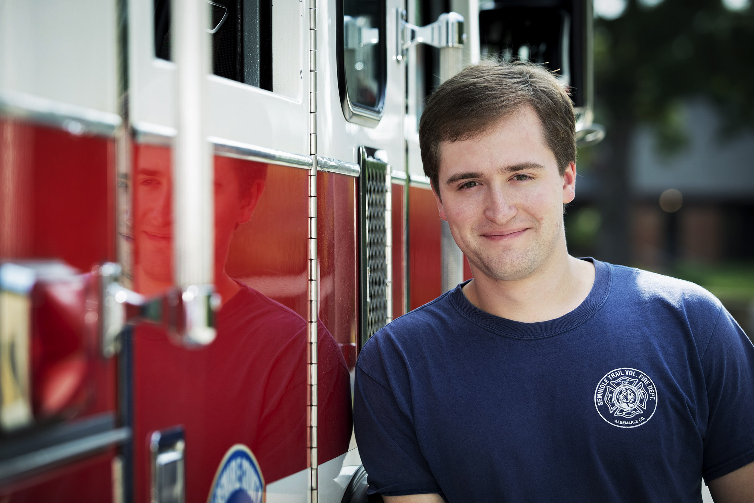 Walker Smith leaning on a Seminole Trail Firetruck looking at the camera smiling