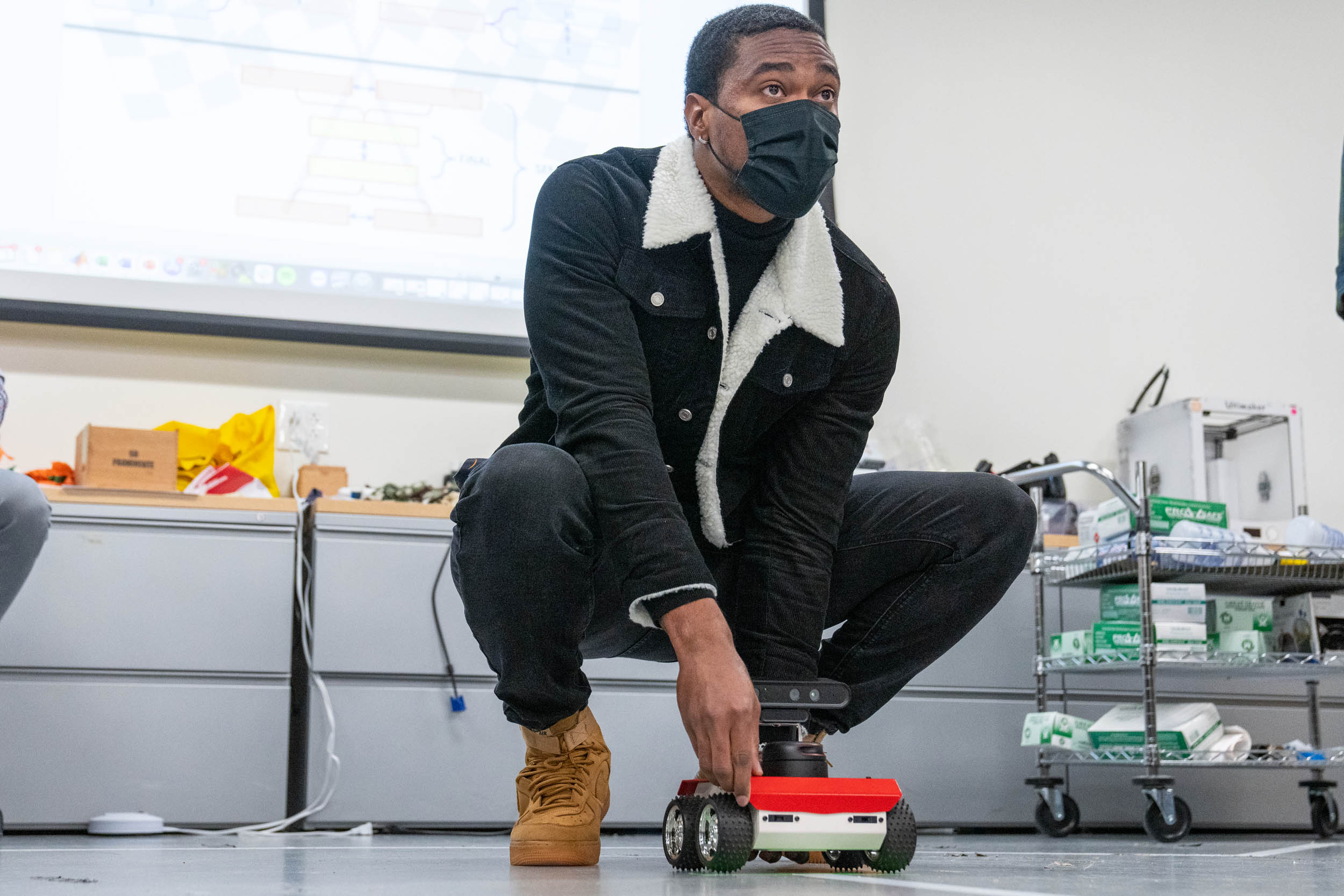 Student bent down with Autonomous Vehicle ready to compete