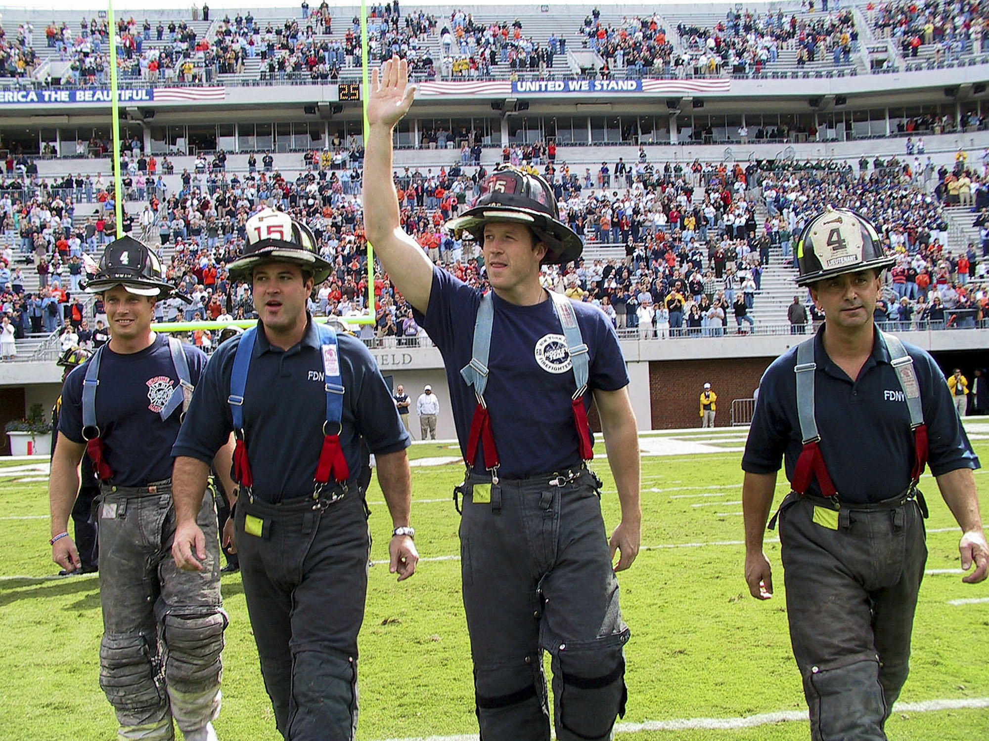 four representatives of the New York City Fire Department – Lts. Jim Milone and Charlie Noseworthy and firefighters Joe Gildea and Rich Amthor walk onto the field