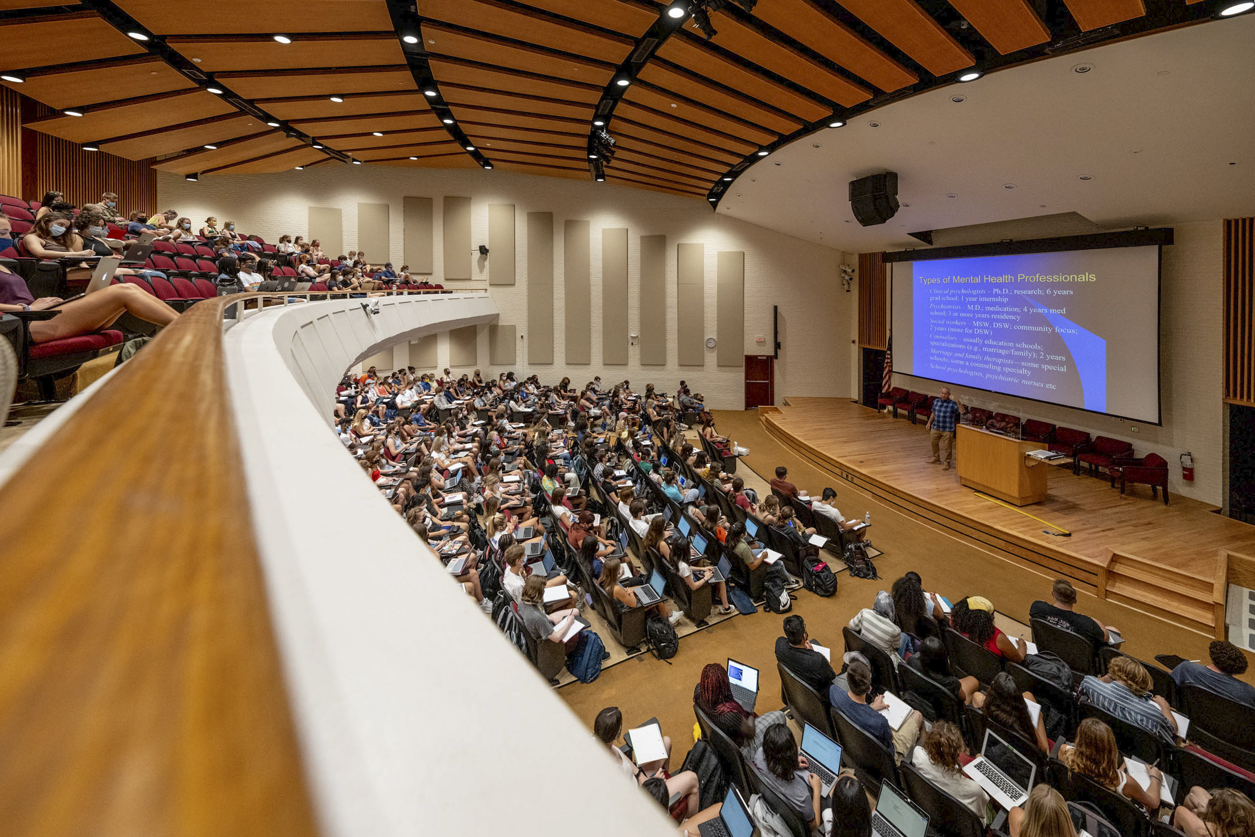 Robert Emery standing on a stage teaching to a full lecture hall