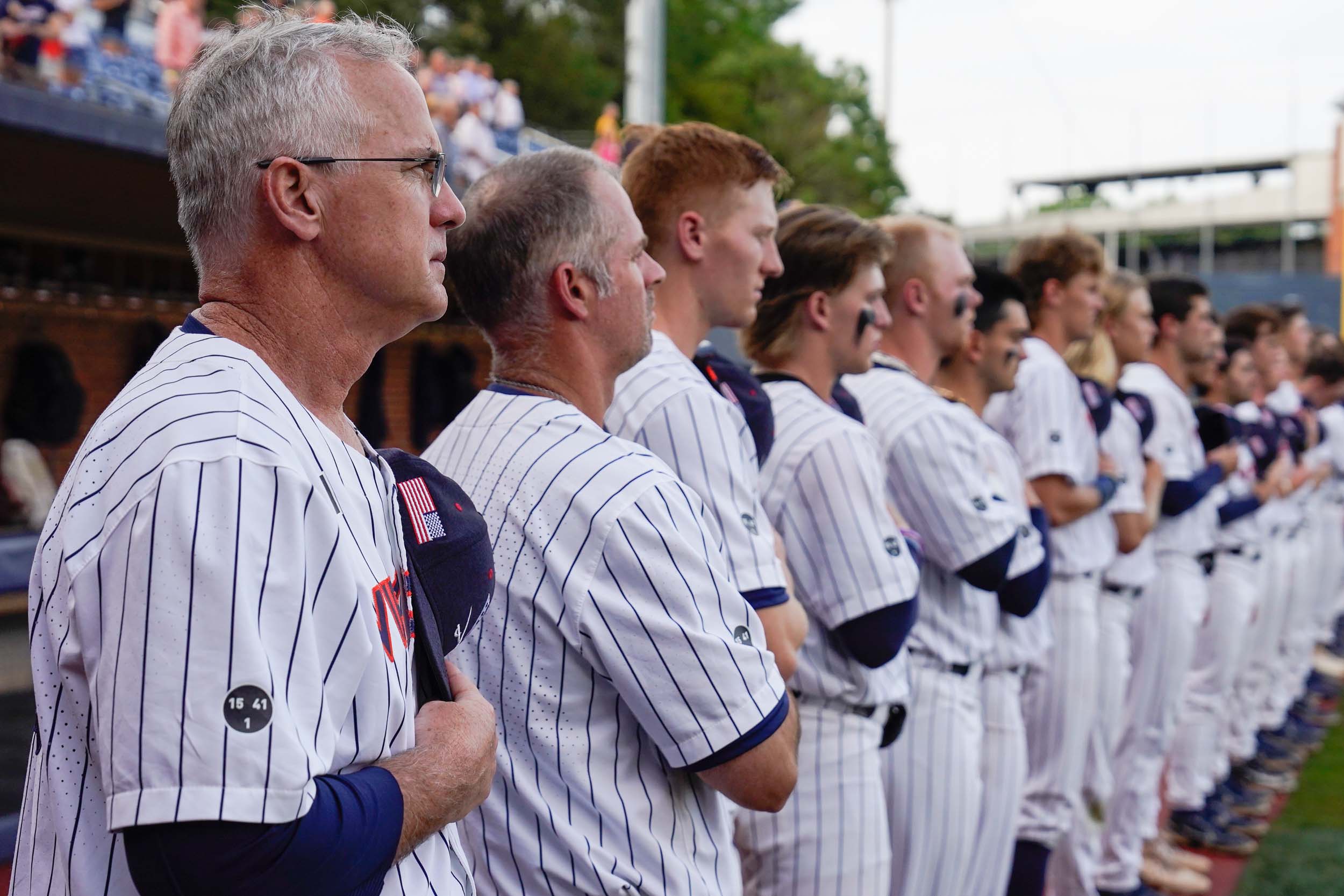 A side view of the U V A baseball team standing for the national anthem