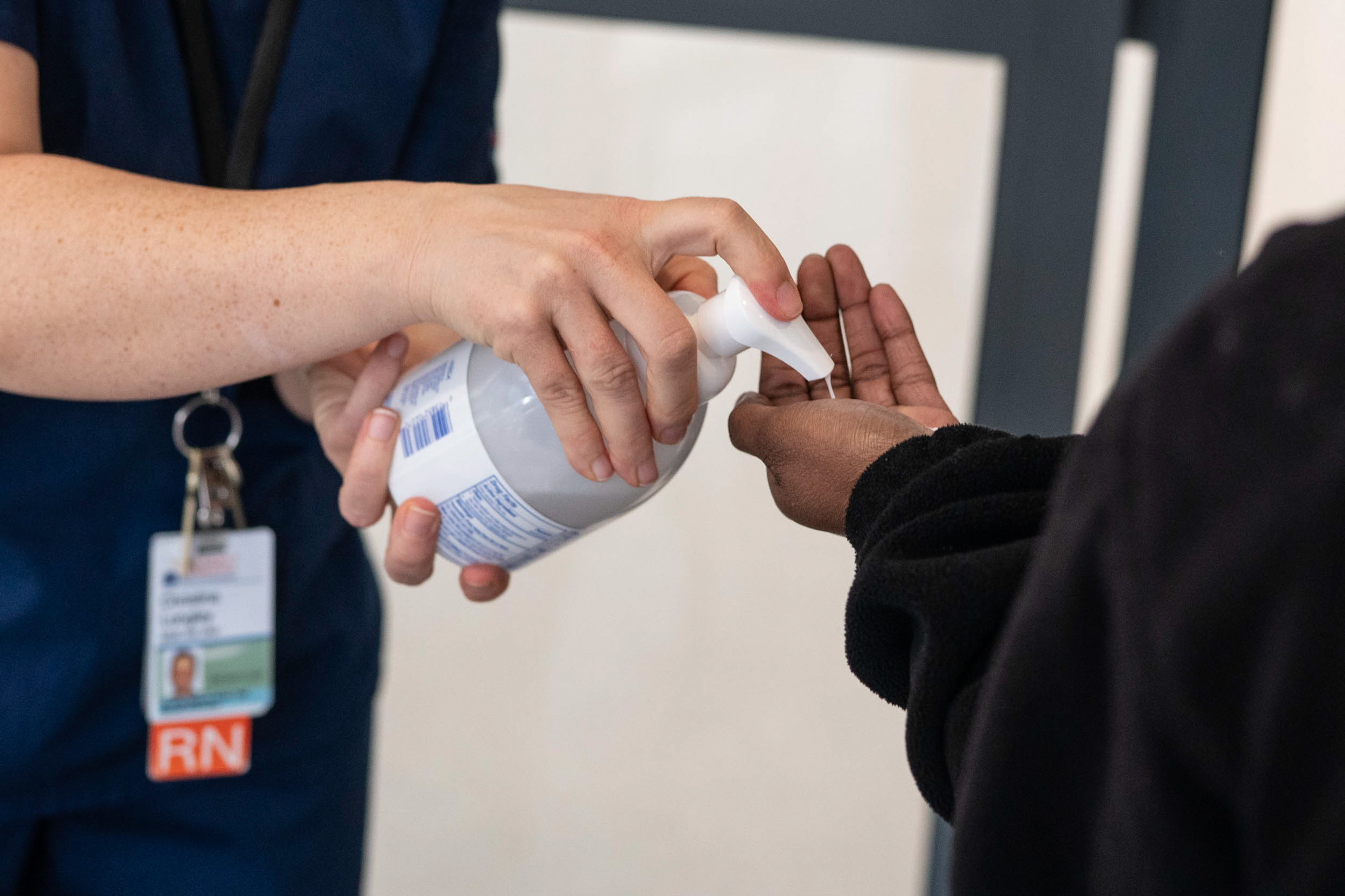 Nurse giving a visitor hand sanitizer 