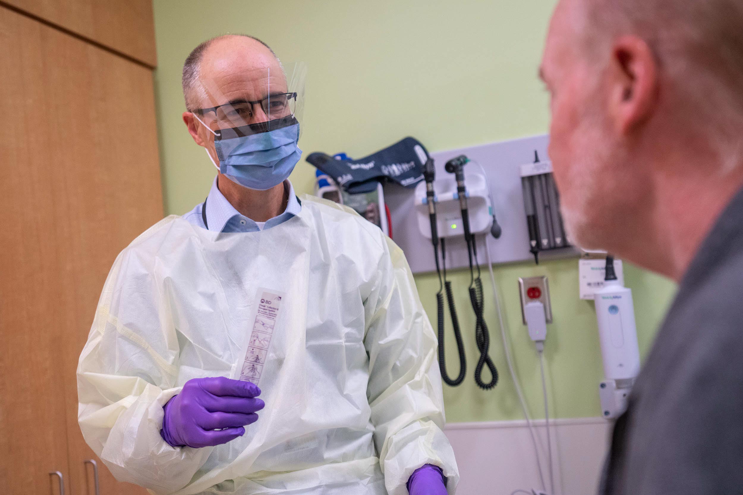 Healthcare provider talking to a patient while holding a Covid-19 testing swab