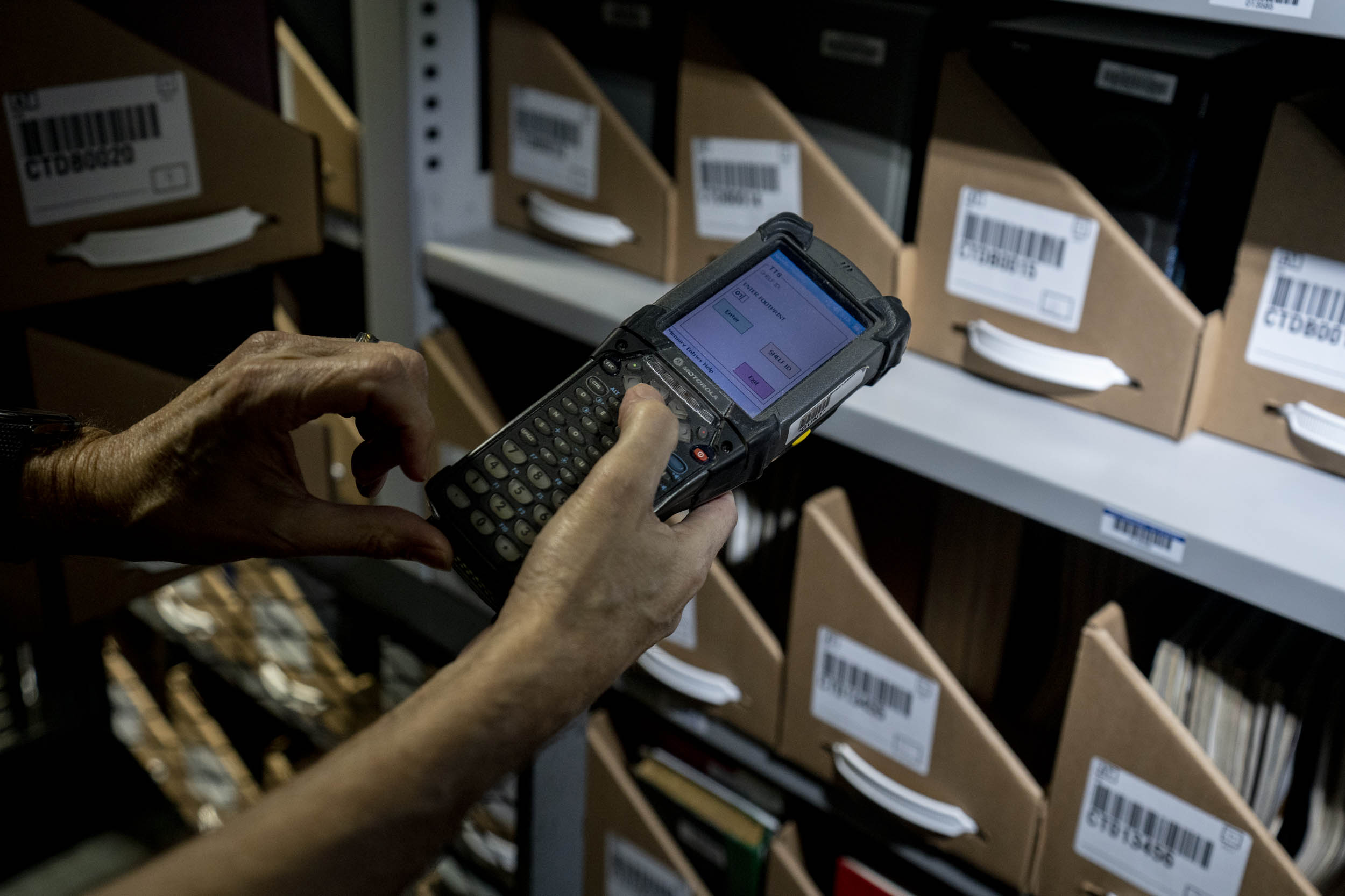 Person holding a hand held scanner to scan the barcodes on cardboard containers