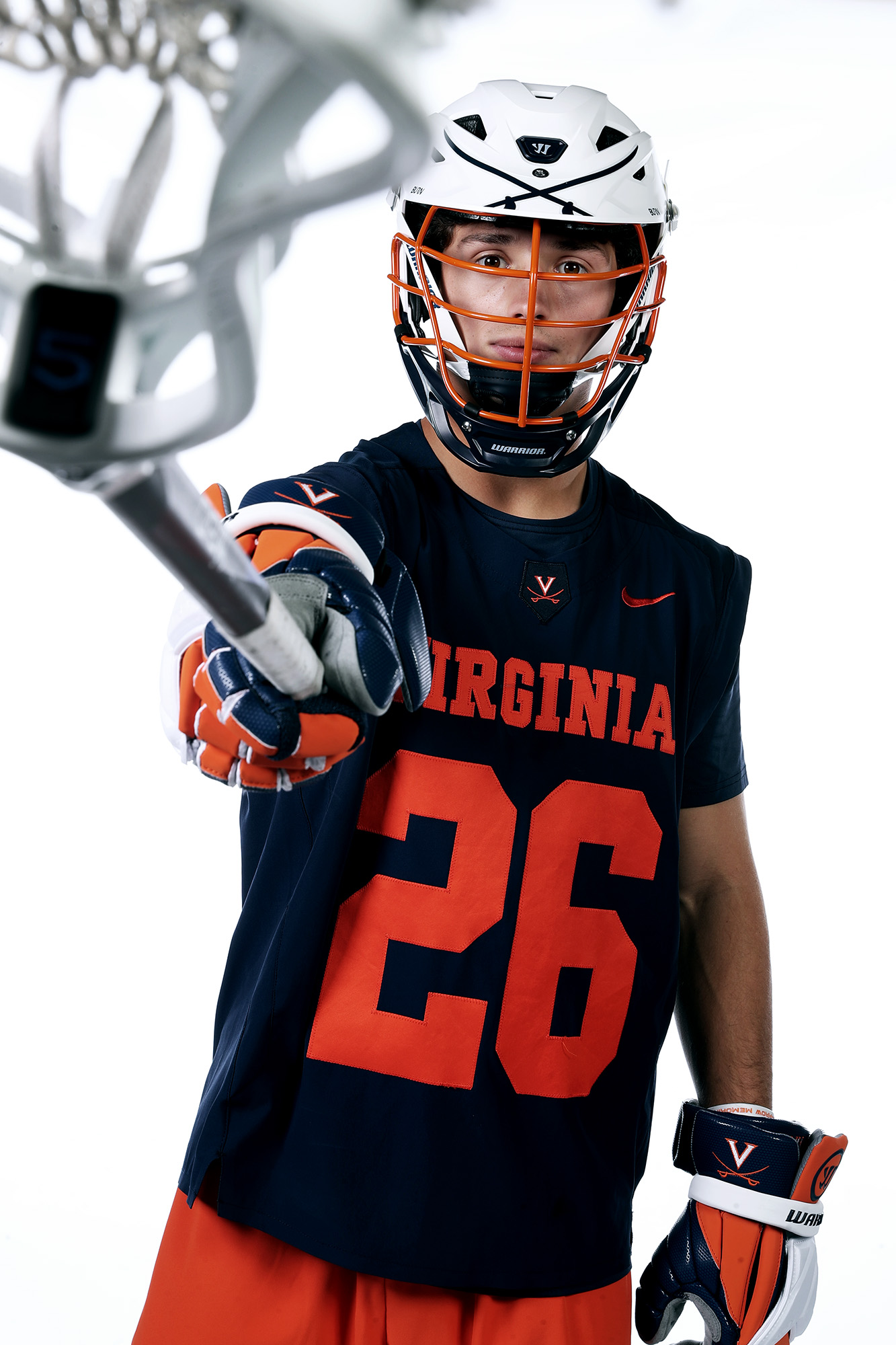 Matt Riley in his Lacrosse Uniform pointing his his lacrosse stick towards the camera