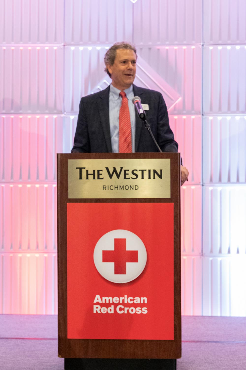 James Hatcher standing at a podium giving a speech to a crowd of Red Cross supporters