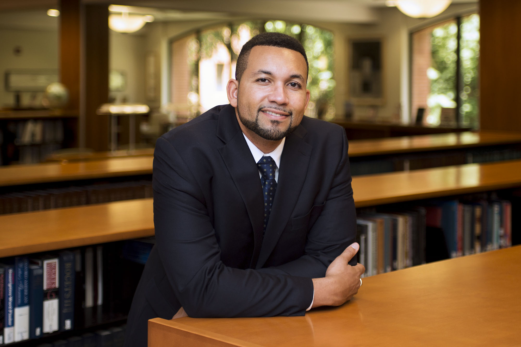 Jay Butler standing in a library looking at the camera