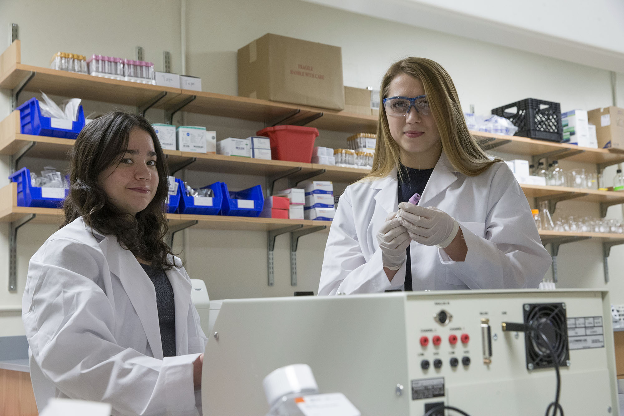 Jess Looby and Lily Berger smile at the camera as they work in a lab