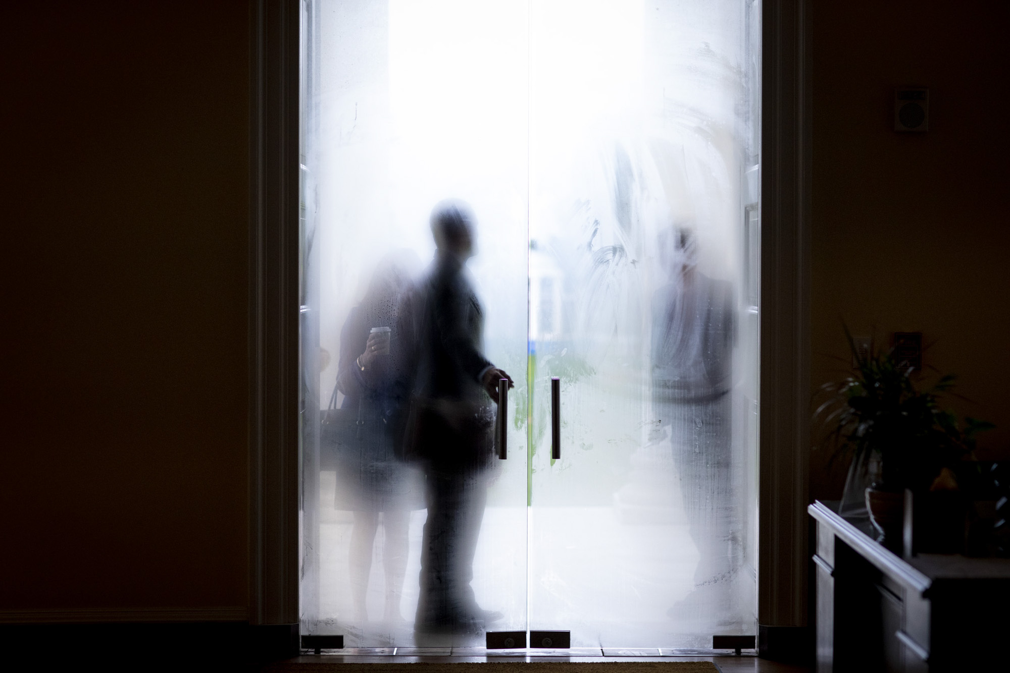 President Jim Ryan reaches for the glass fogged door of a building