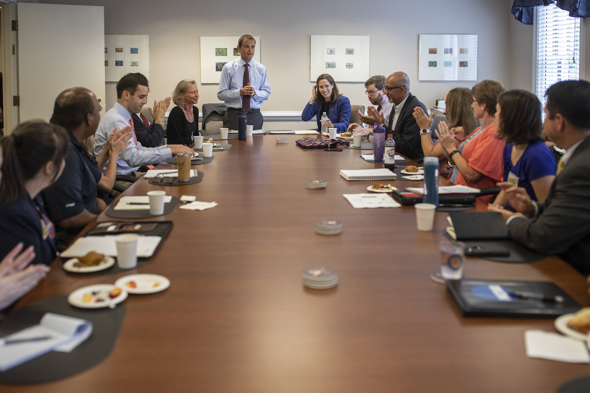 President Jim Ryan stand at the head of a table full of people who are clapping