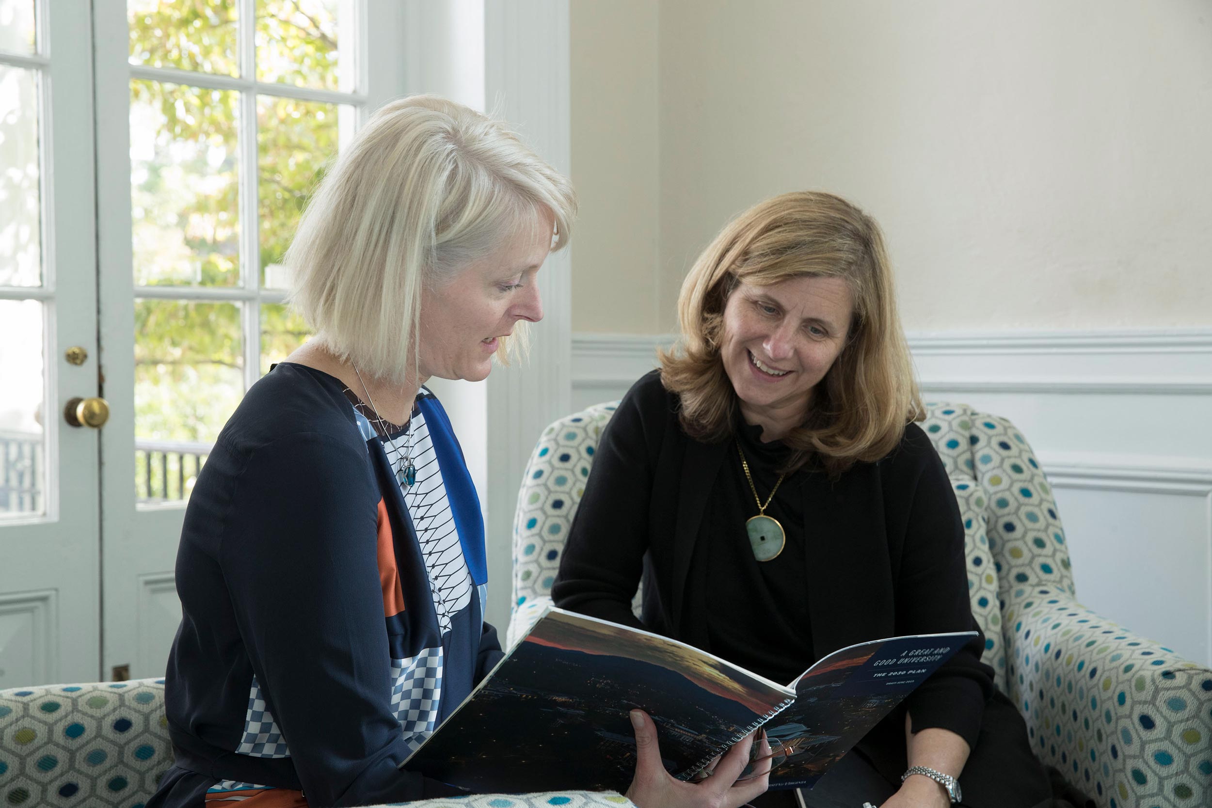 Jennifer “J.J.” Wagner Davis, left, Elizabeth “Liz” Magill, right look at a book together