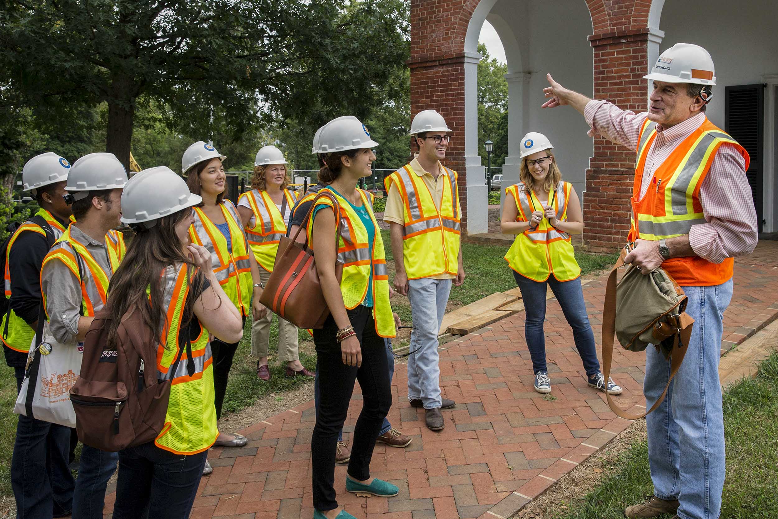 Jody Lahendro in construction hat and vests talkings to a group of students who are also dressed in construction hats and vests