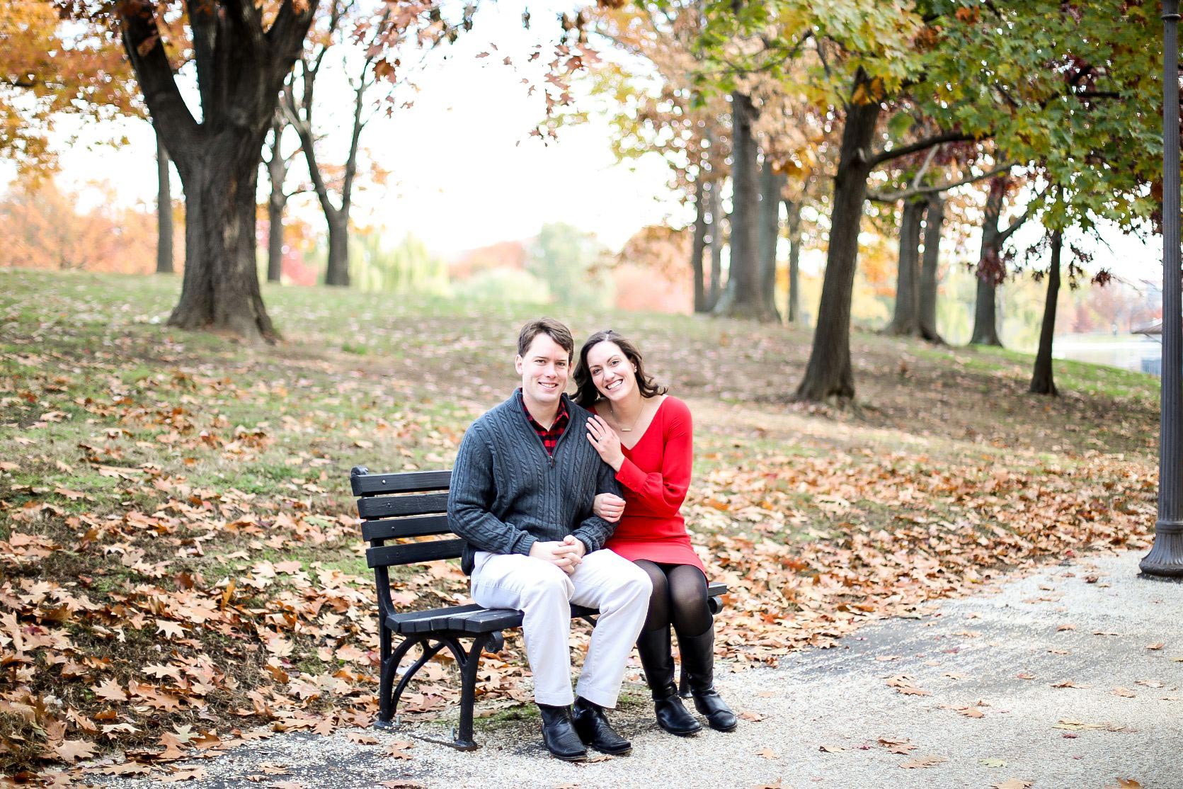 Joe Riley and his wife Rachel sitting on a bench with fallen leaves posing for a picture
