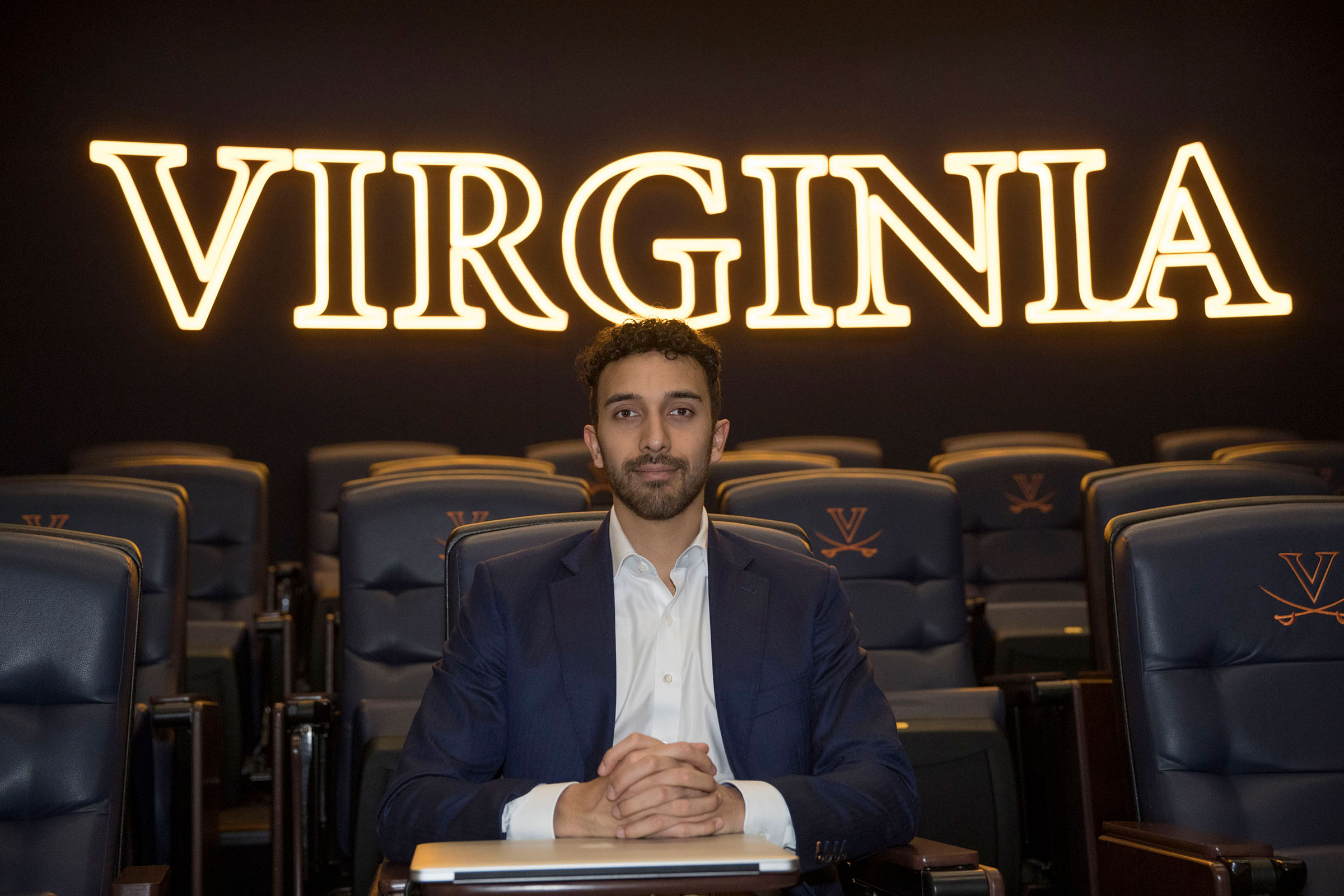 Johnny Carpenter sits in a chair with neon lights spelling Virginia