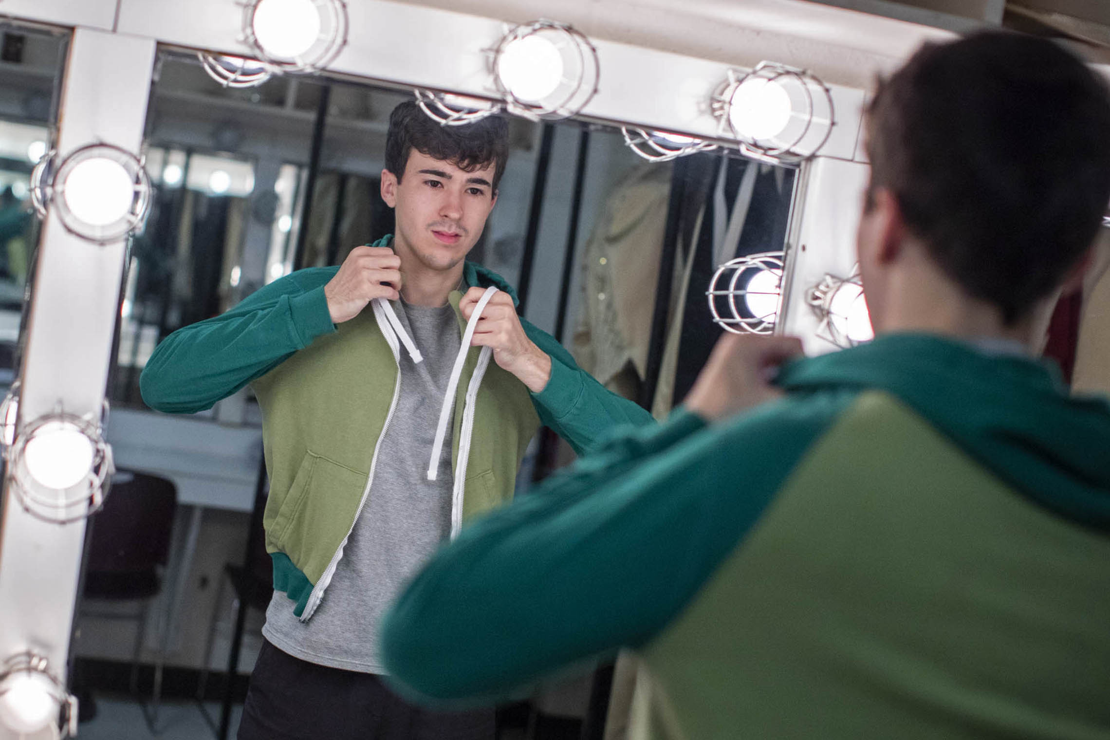 Sanchez putting on a jacket in a backstage mirror