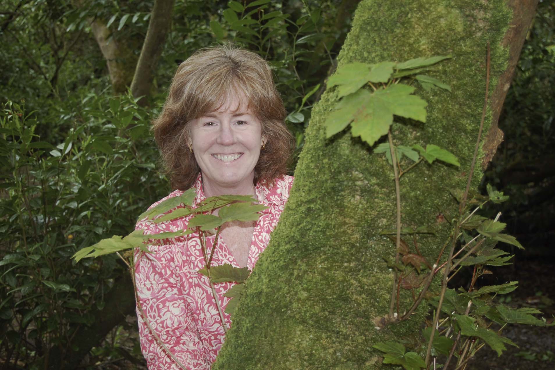 Kristin Miller stands behind a tree for a headshot