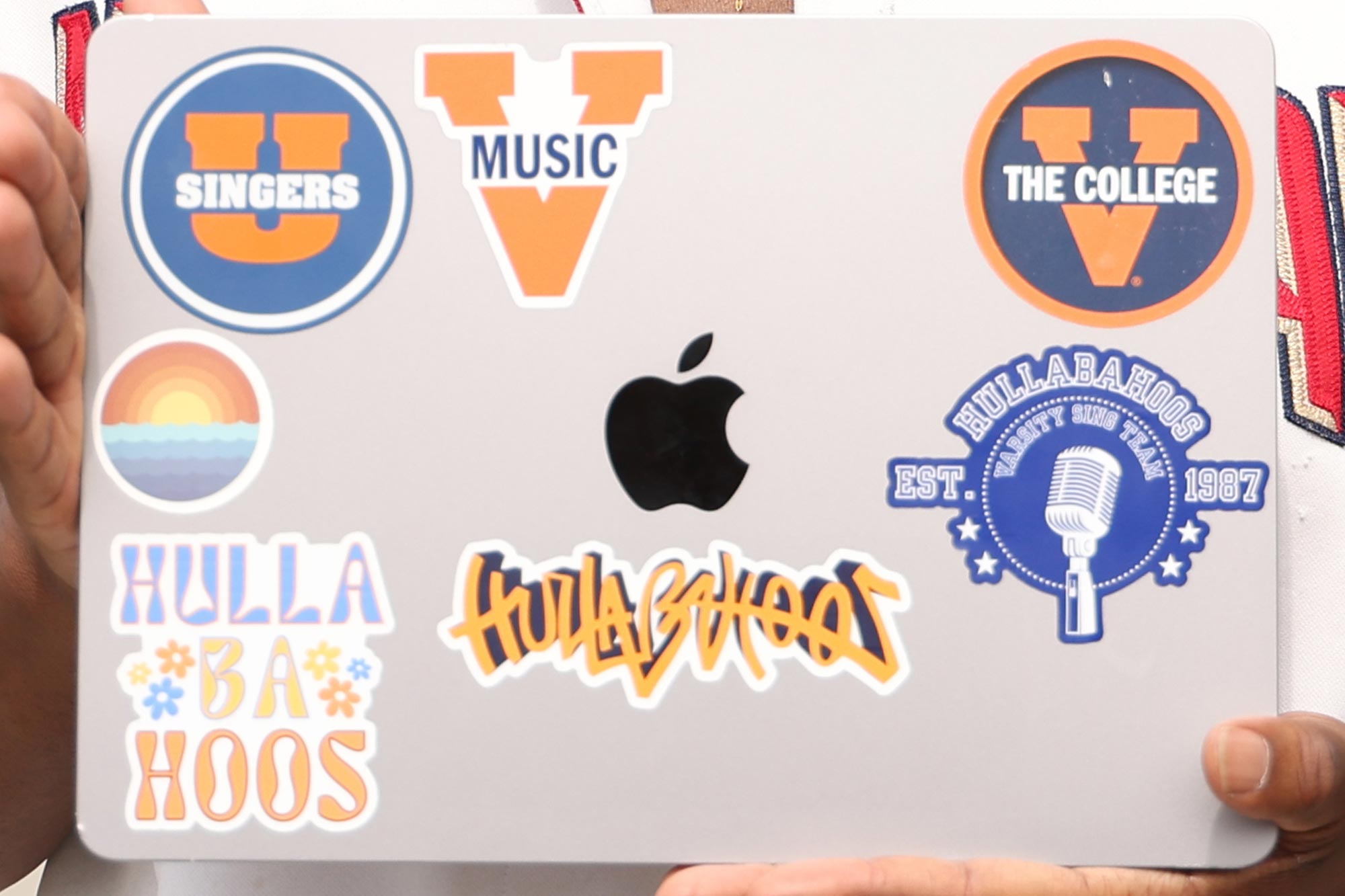 Godwin Mensah's laptop covered in UVA choral and music stickers, representing his involvement in University Singers and Hullabahoos.