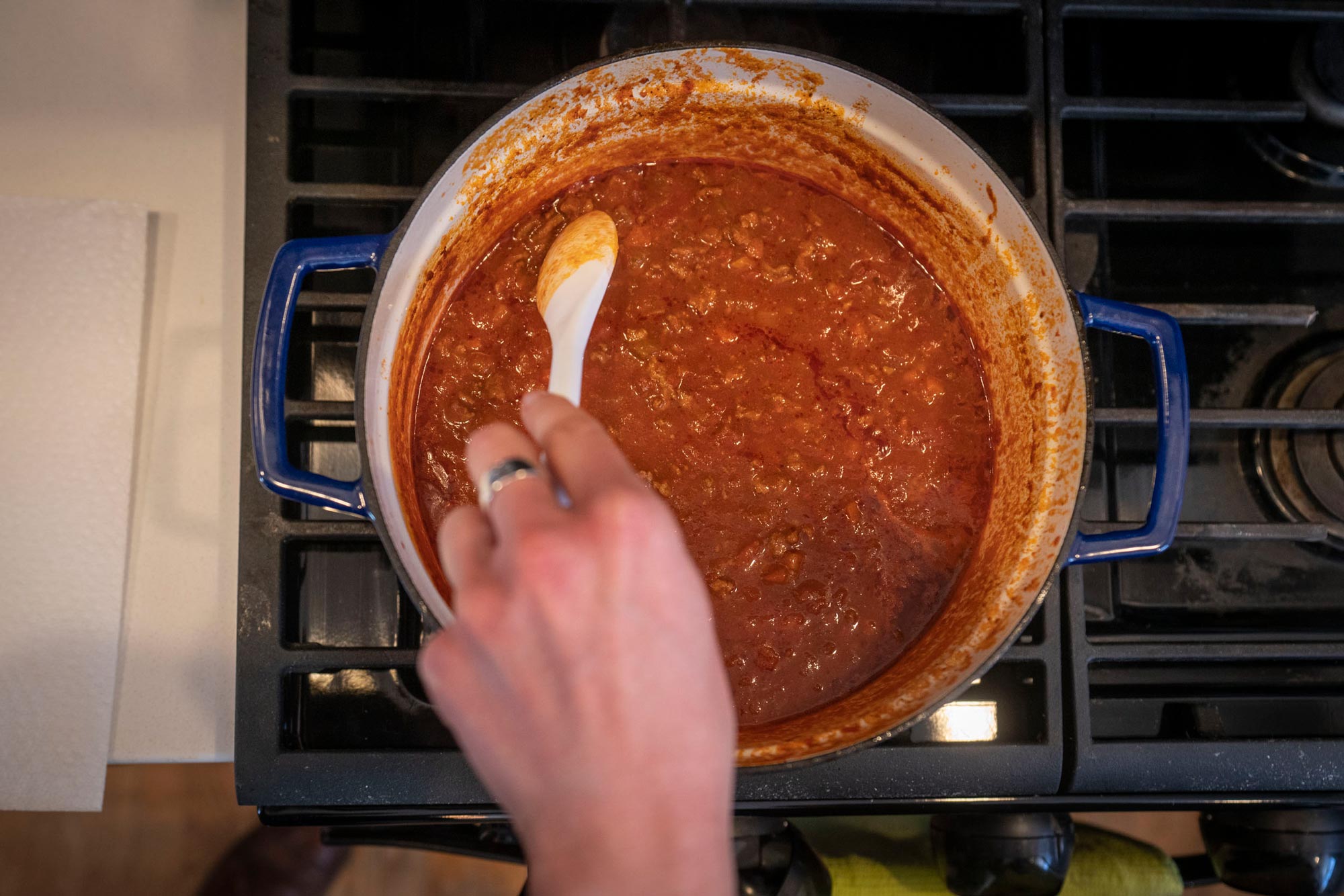 Person stirring a meat sauce on a stove