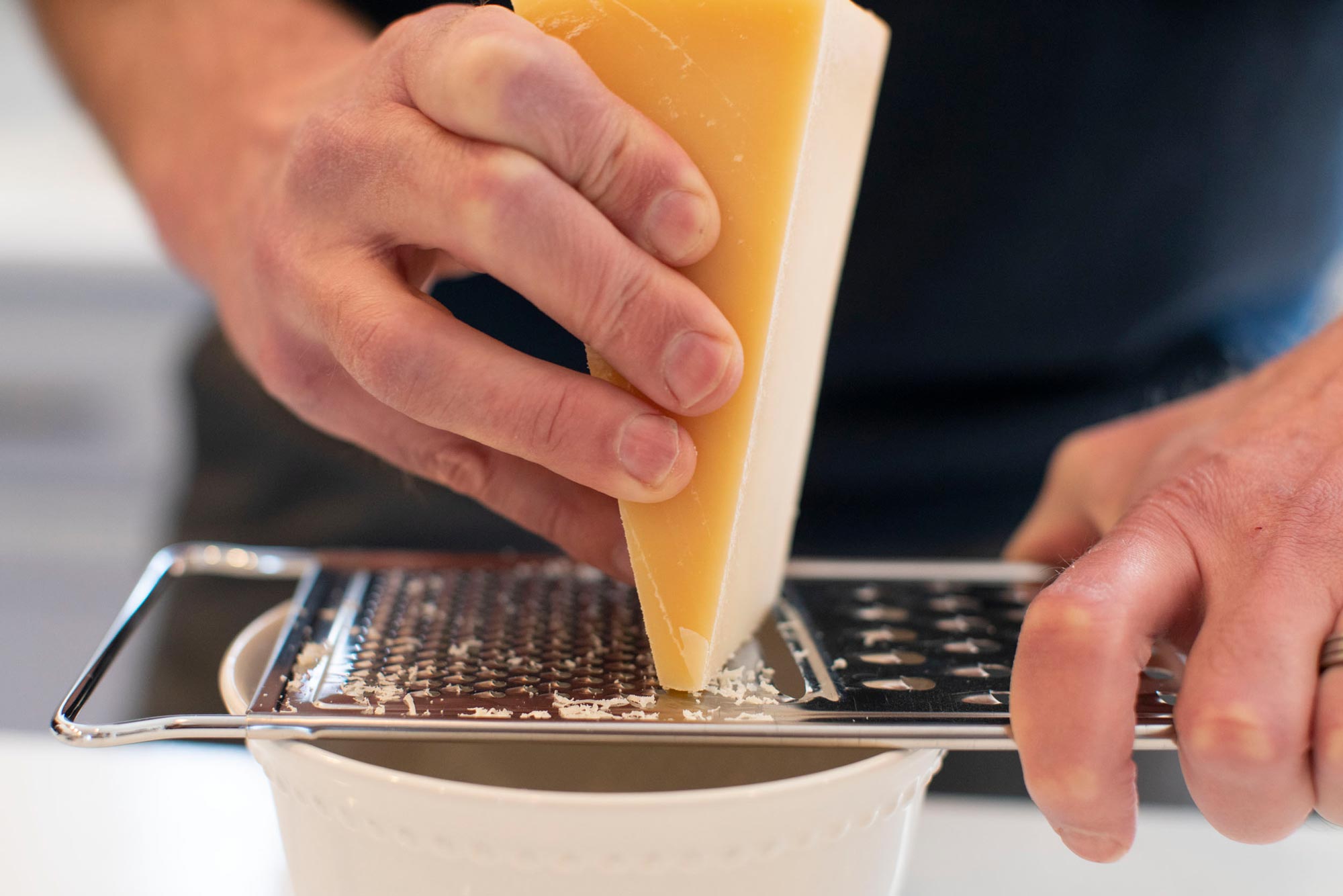 Person grating cheese into a bowl