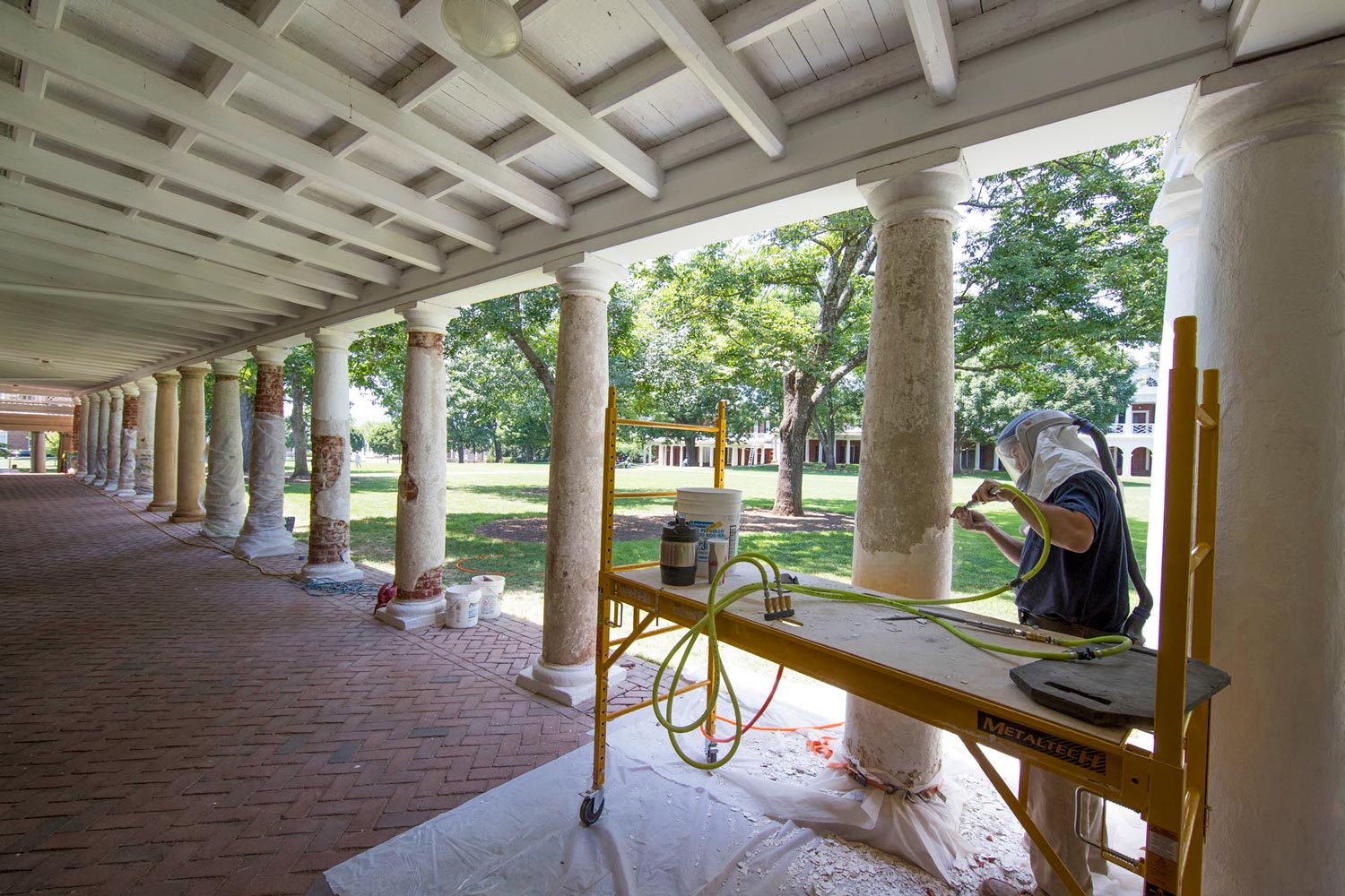 A UVA mason carefully removes the outer covering a Tuscan column on the Lawn.