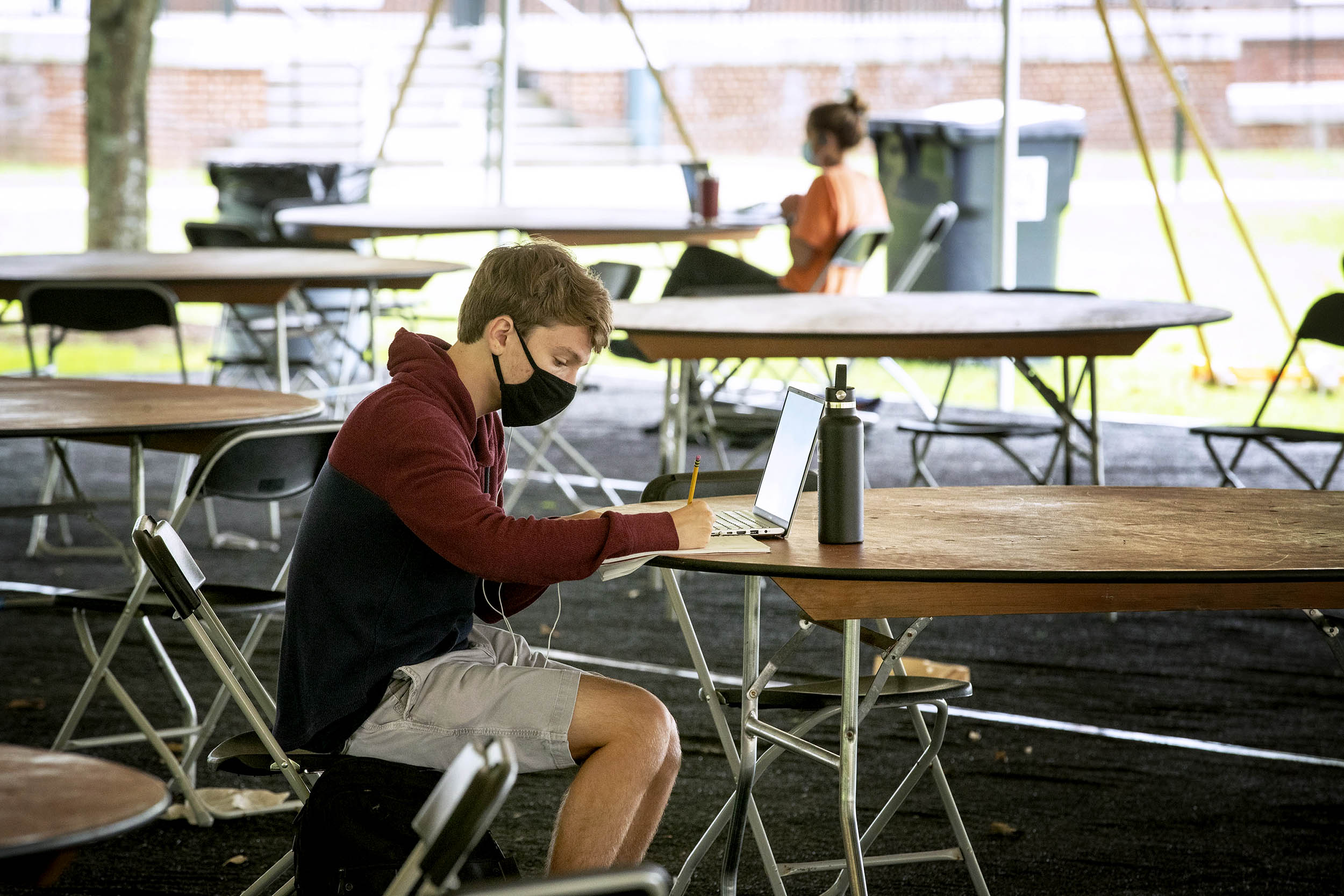 Student sitting at a table under a tent working