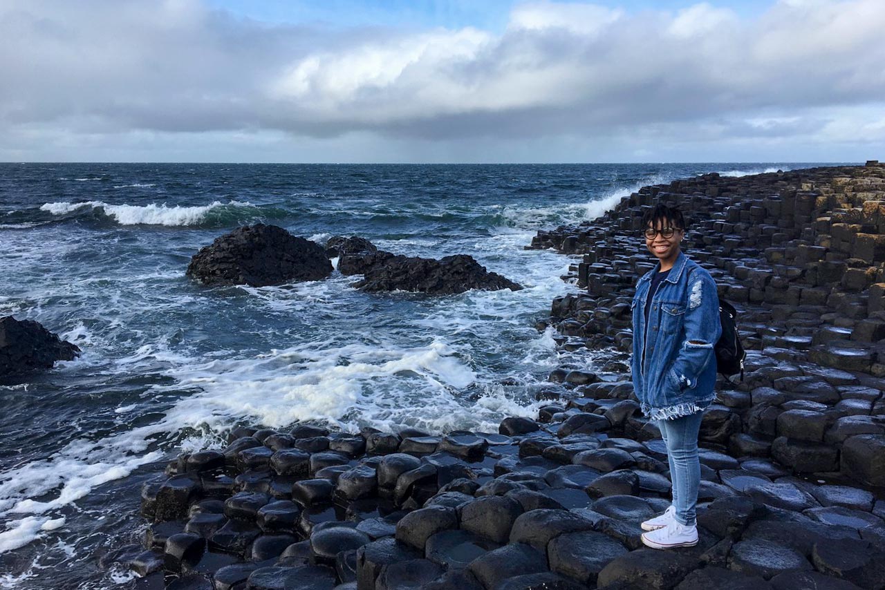 Autumn Swain stands on wet rocks at the ocean in London