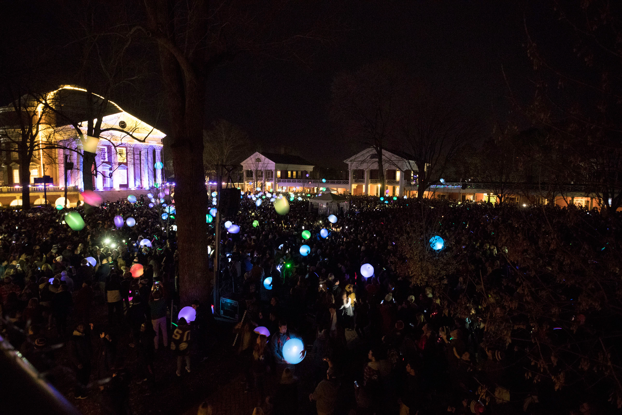 Thousands of students, faculty, staff and community members stand on the lawn with lit up balloons 