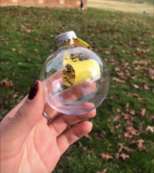 Person holding a clear ornament with a yellow piece of paper inside of it