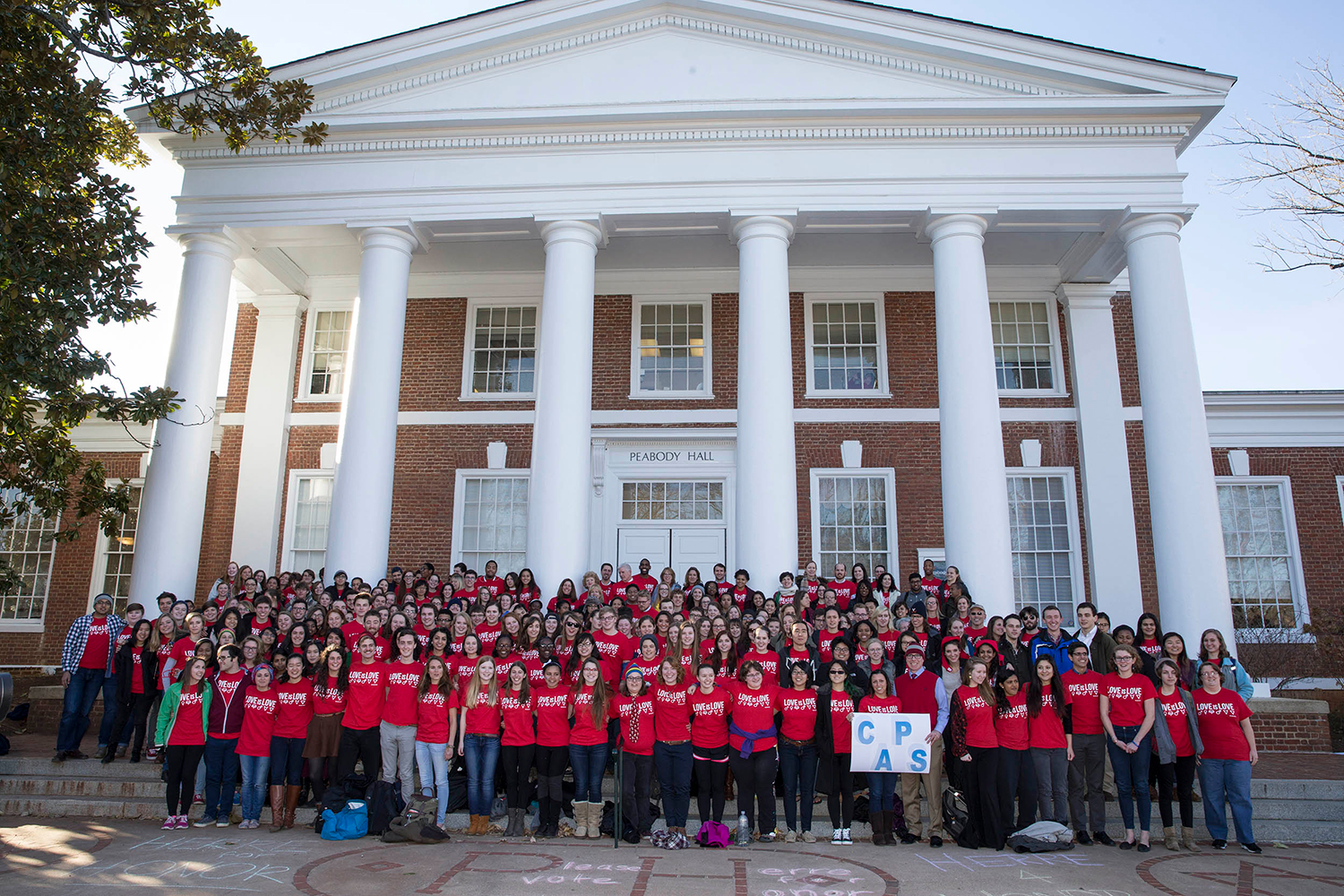 people in front Peabody Hall wearing red shirts that say Love is Love