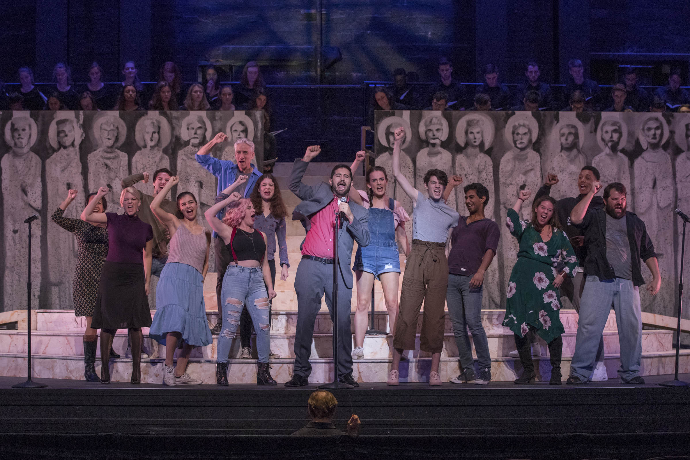 Theatre performers singing and raising their fists