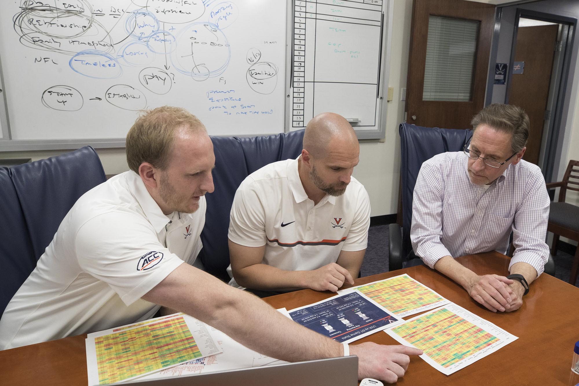 Matt Edwards, left, and Justin Anderson, center, Bill Scherer, right sit at a table looking at papers