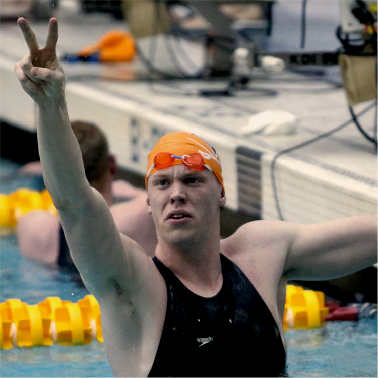 Matt Mclean raises one hand to the stage after a swimming heat