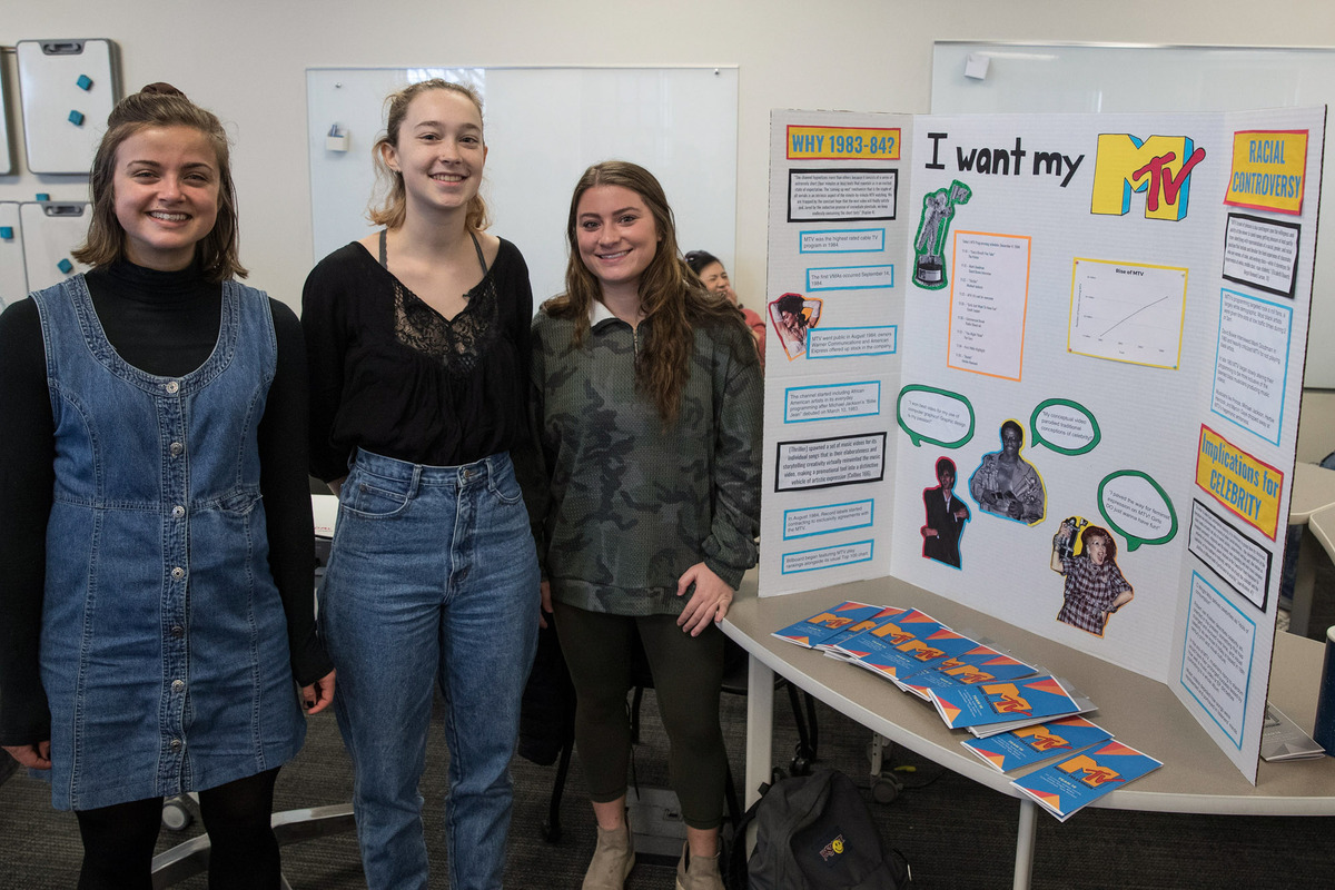 Students stand next to their tri-fold that reads I want my Mtv