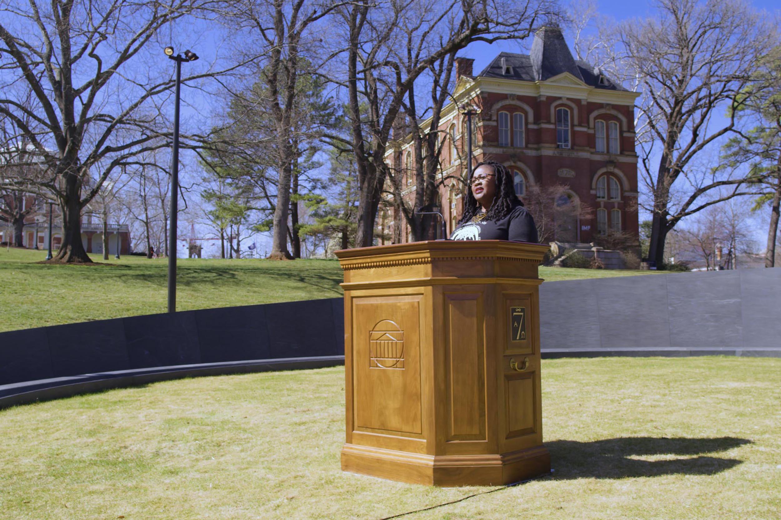 Woman speaking at a podium at the Memorial of Enslaved Laborers