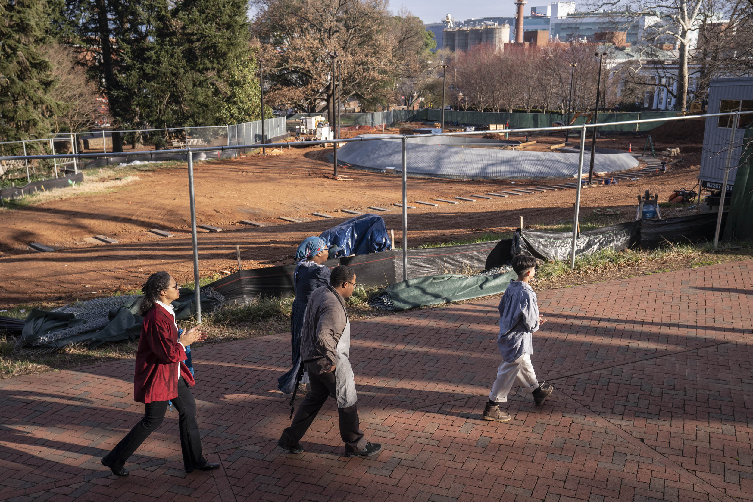 People walking past the Memorial of Enslaved Laborers construction site