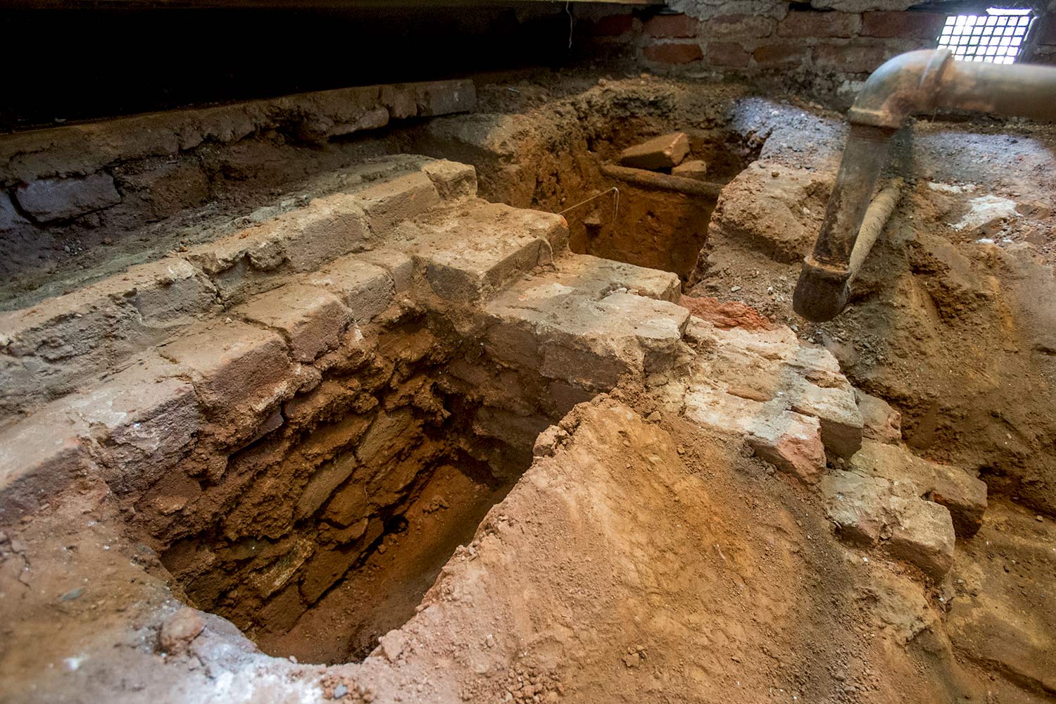Archaeologists examine a thick foundation for an extension on the west side of the original kitchen structure. Researchers do not yet know for what the extension was used. 