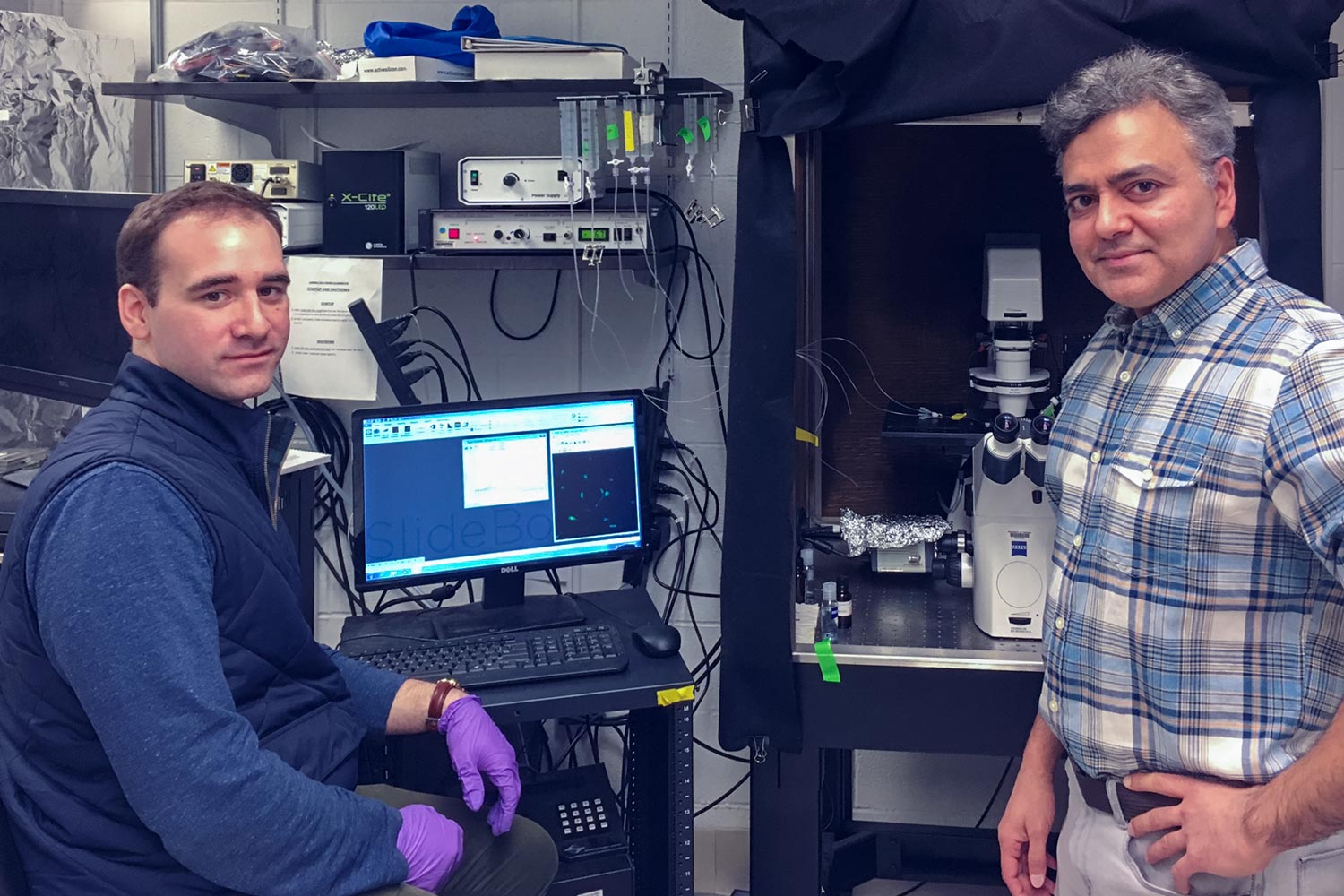 Researchers Michael Schappe, left, and Bimal Desai stand at a computer