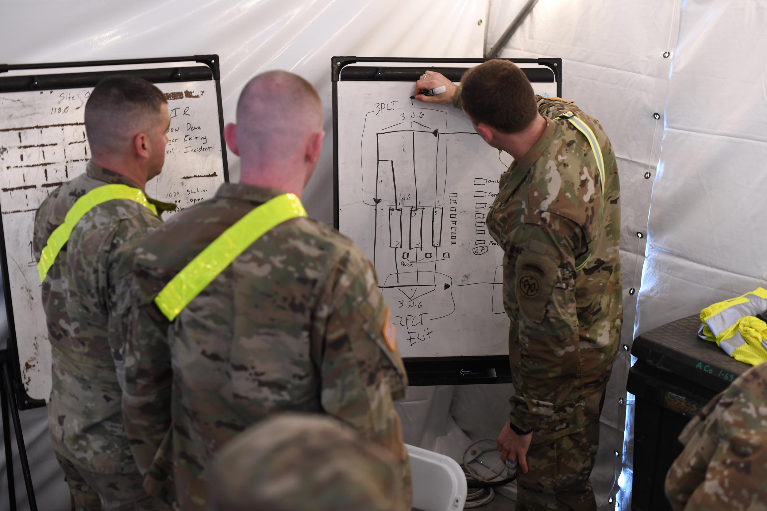 US Service members looking at another member drawing on a white board