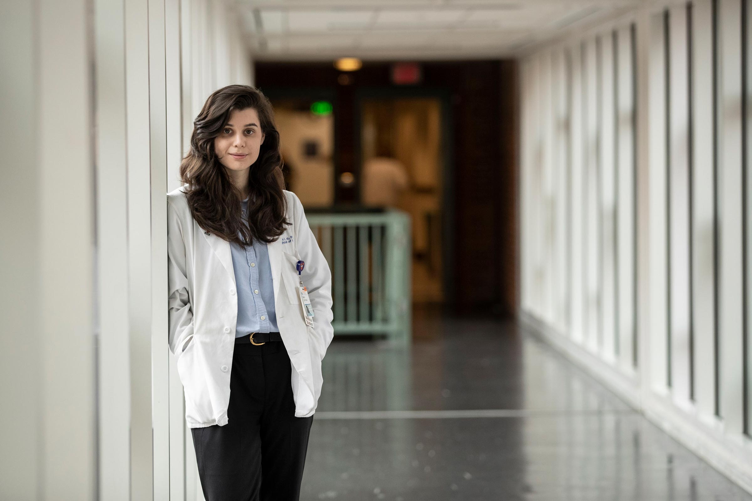 Mira du Plesses leaning against a wall in a short white coat