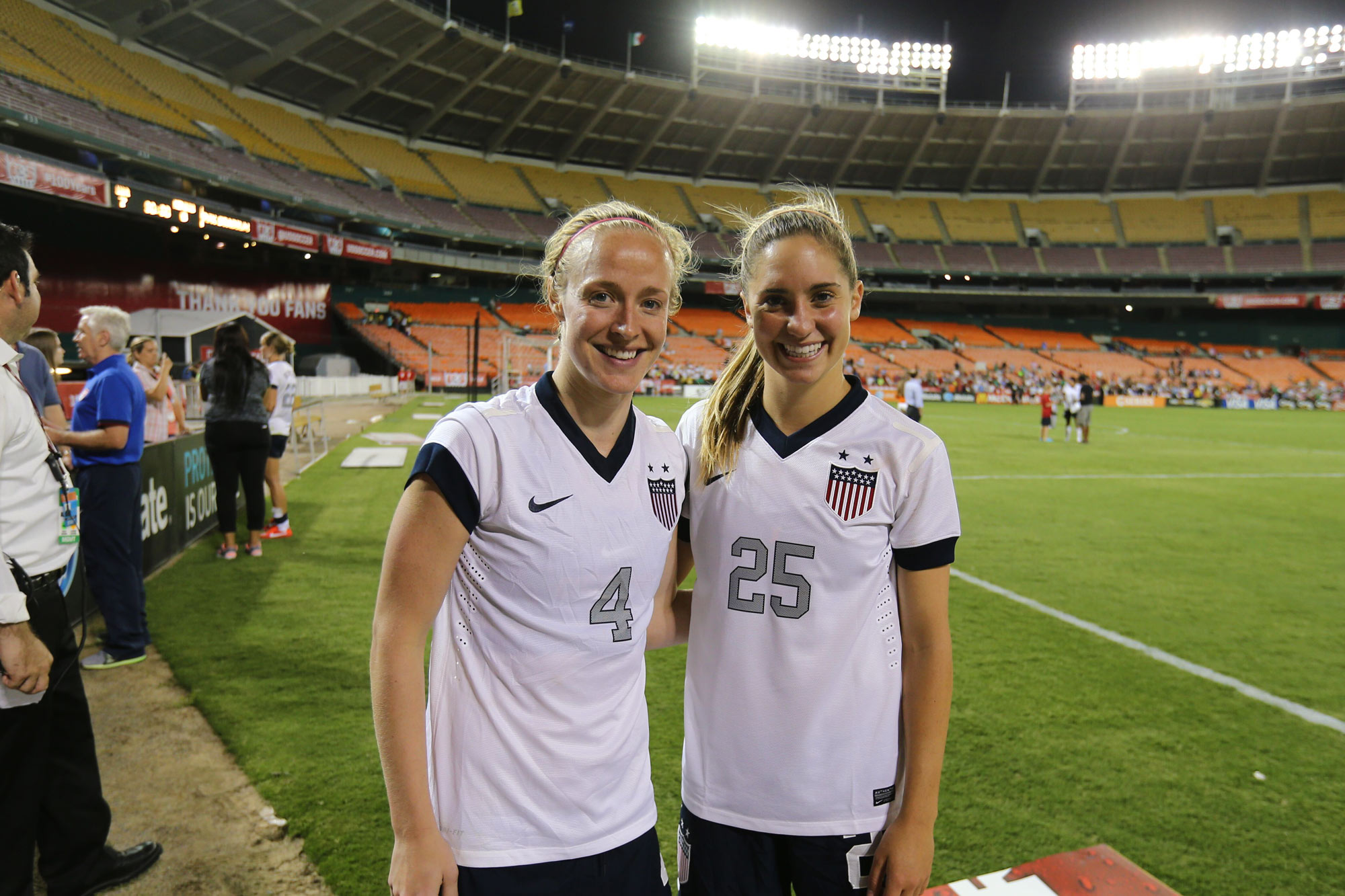 Former Cavaliers Becky Sauerbrunn and Brian stand together on a soccer field smiling for the camera