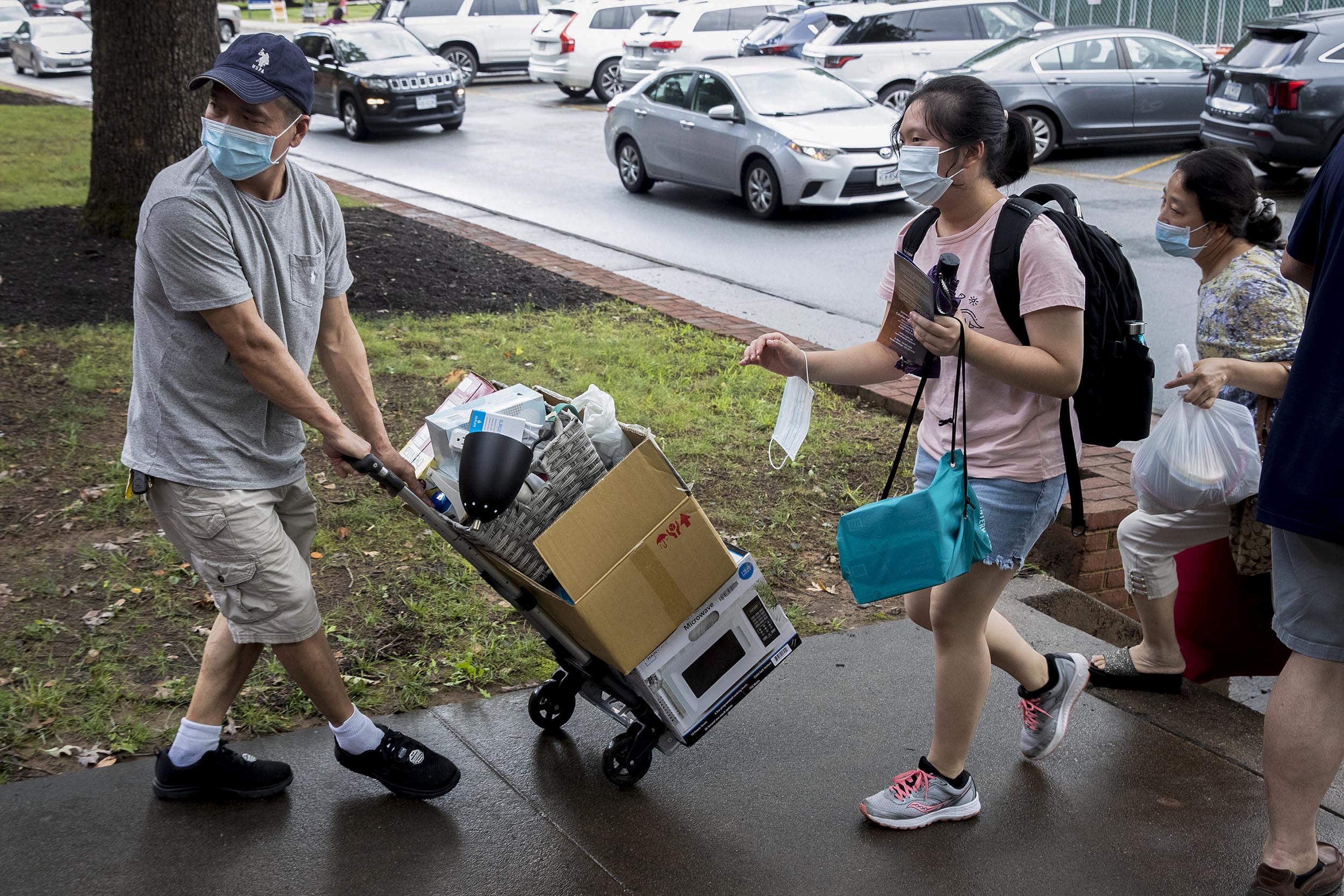 People carrying personal belongs into a dorm