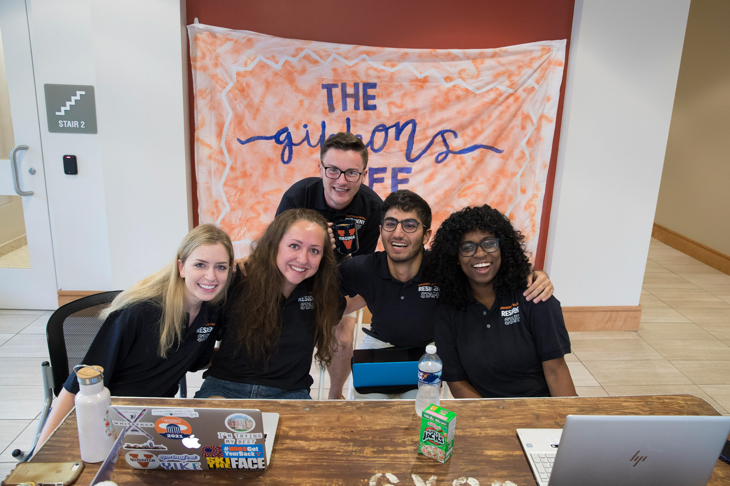 Elizabeth Gillespie, far left, and her team sit at a desk together smiling