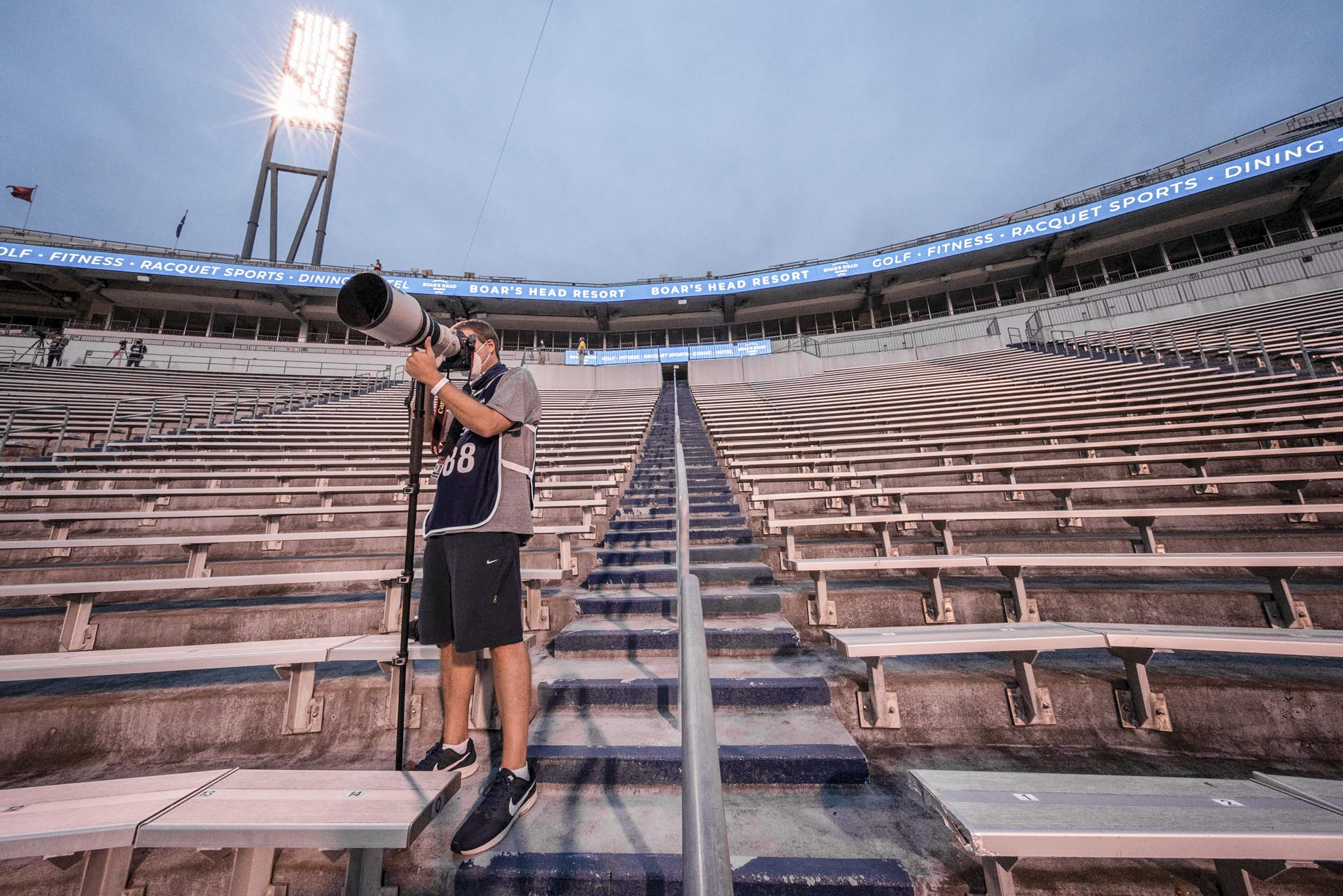 Matt Riley standing in the Scot stadium taking a photo of the field
