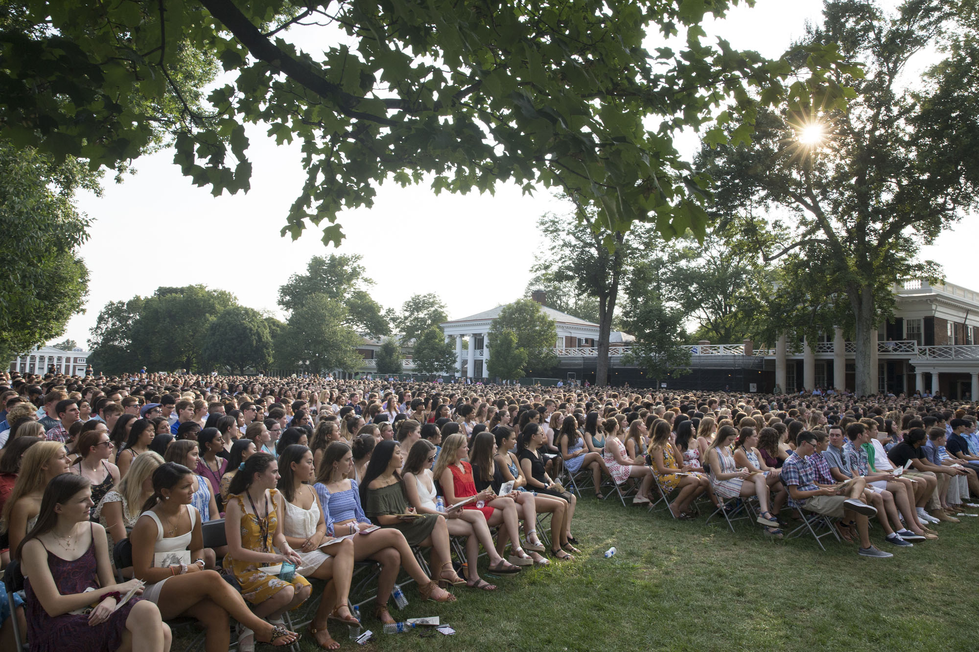 First year students sit in chairs on the lawn listening to speakers