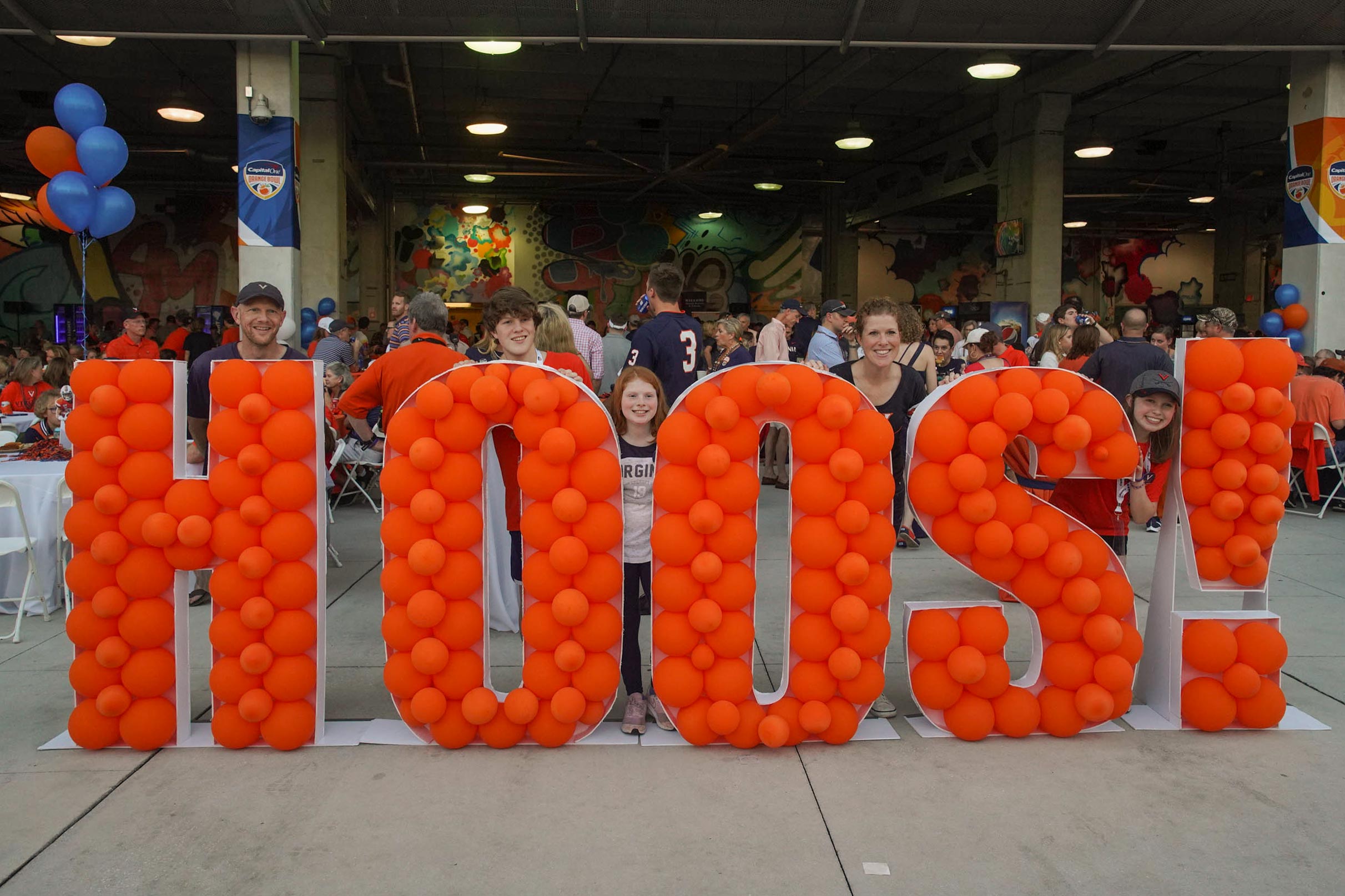 UVA Fans take a family photo with a balloon sculpture that spells HOOS!